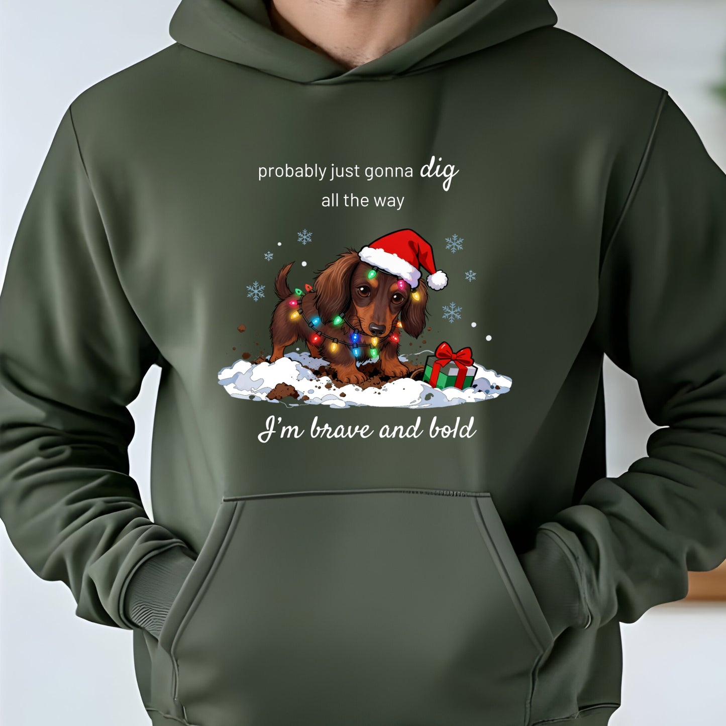 Green hoodie with a Christmas-themed graphic of a dog wearing a Santa hat and lights, text 'probably just gonna dig all the way I'm brave and bold'.
