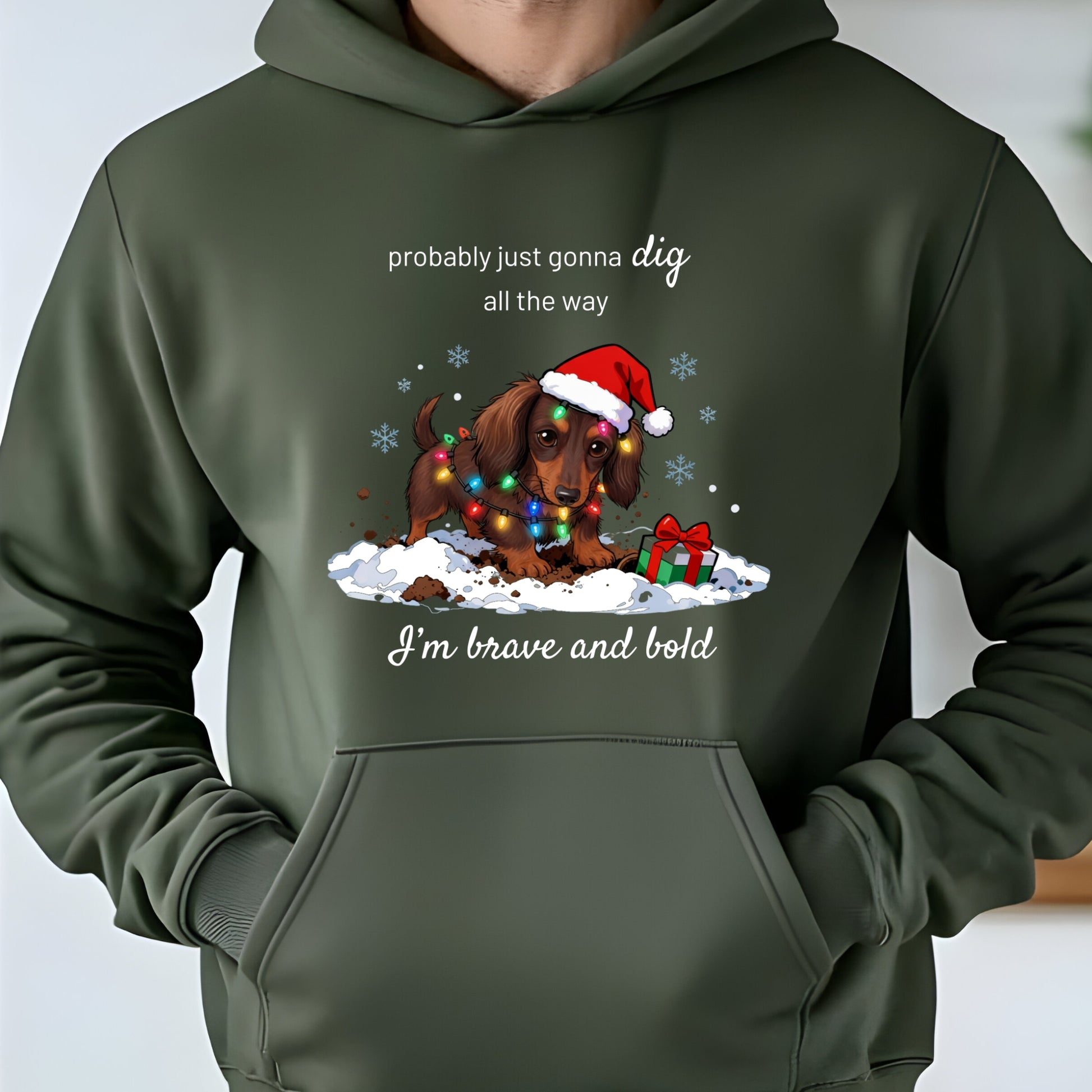 Green hoodie with a Christmas-themed graphic of a dog wearing a Santa hat and lights, text 'probably just gonna dig all the way I'm brave and bold'.