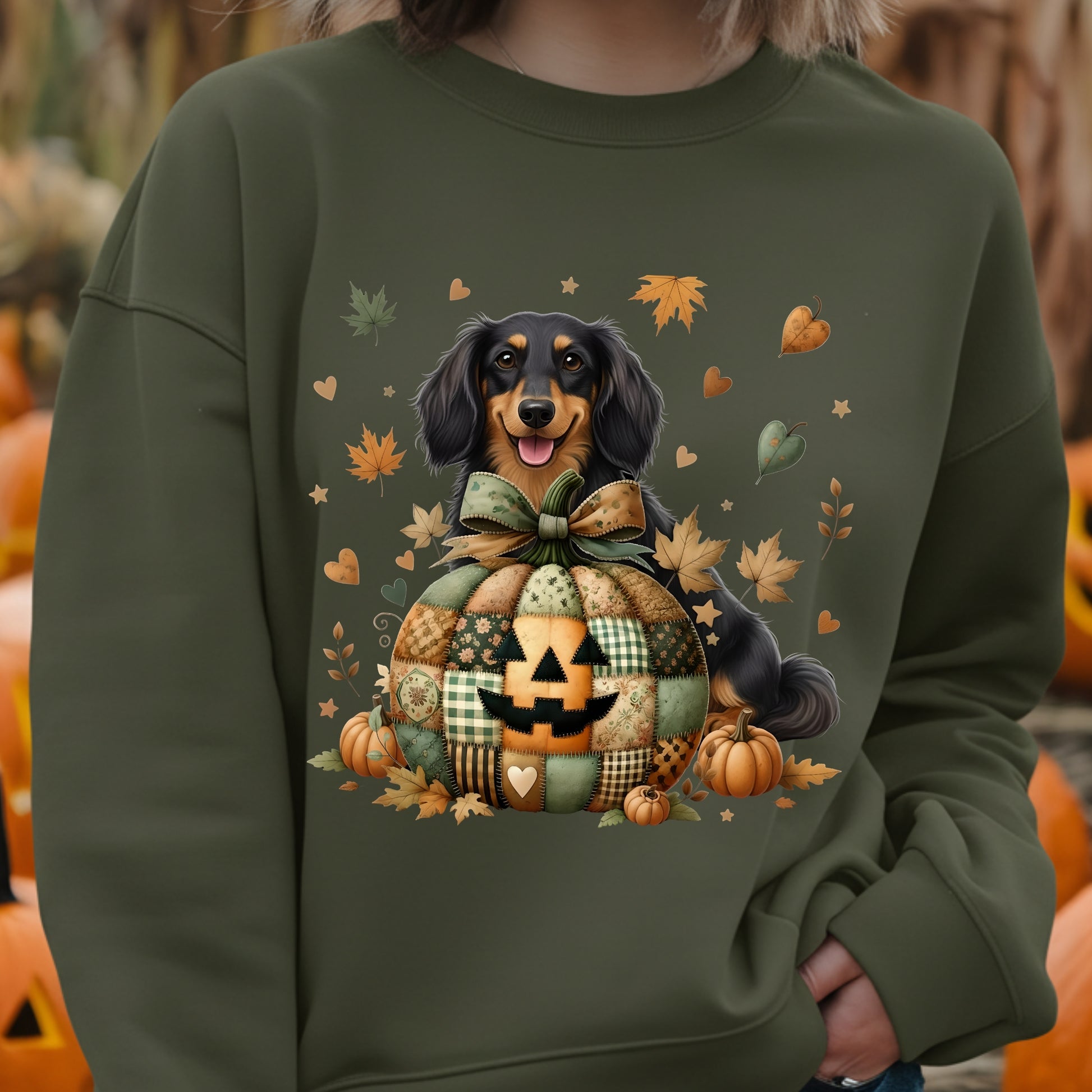 Person wearing a green sweatshirt with a Halloween-themed design featuring a dog and pumpkins.