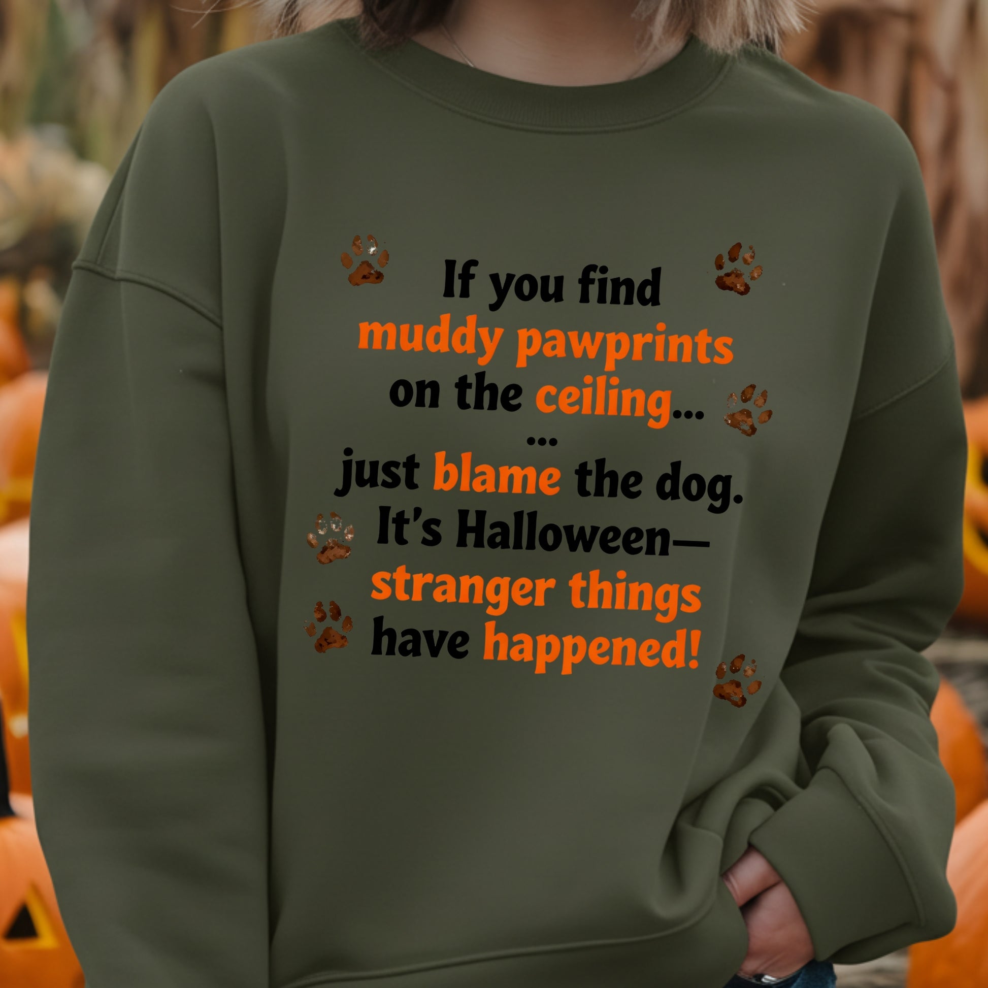 Person wearing a green sweatshirt with Halloween-themed text and pumpkin decorations in the background