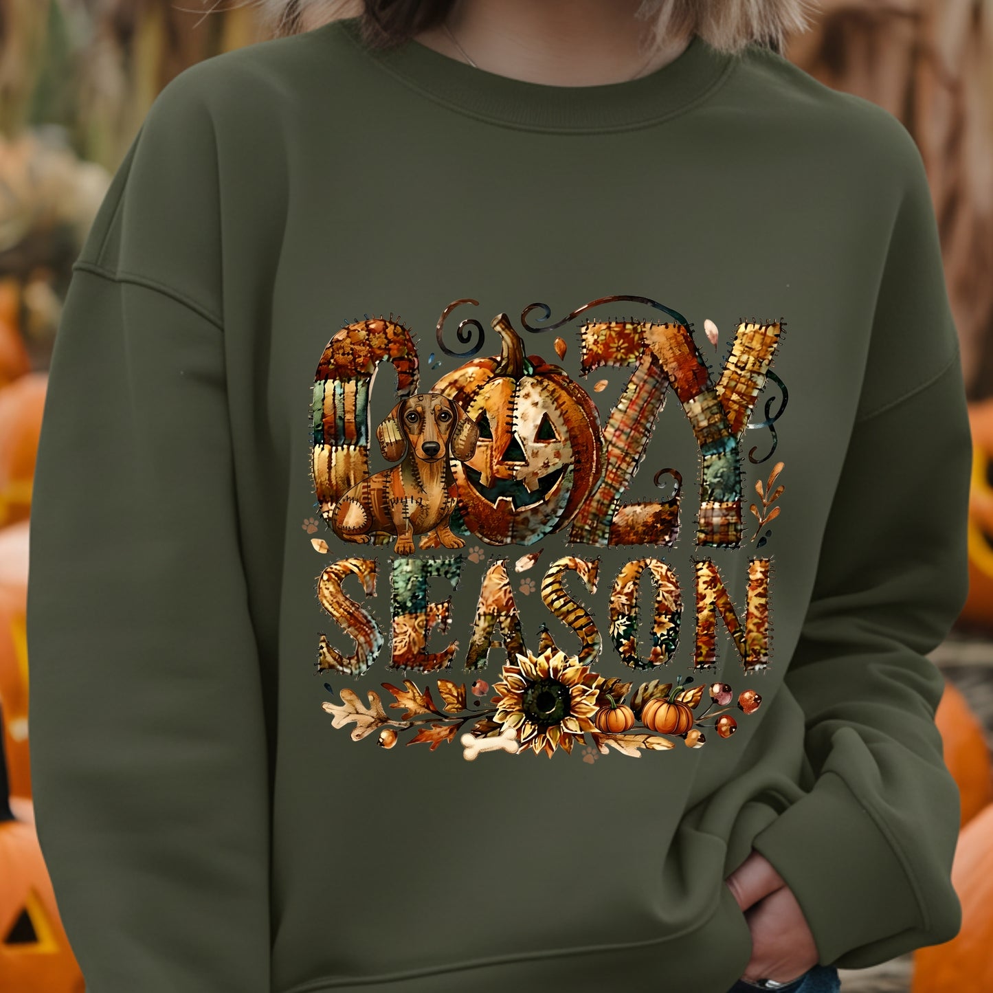 Person wearing a green sweatshirt with 'Spooky Season' design in front of pumpkins.