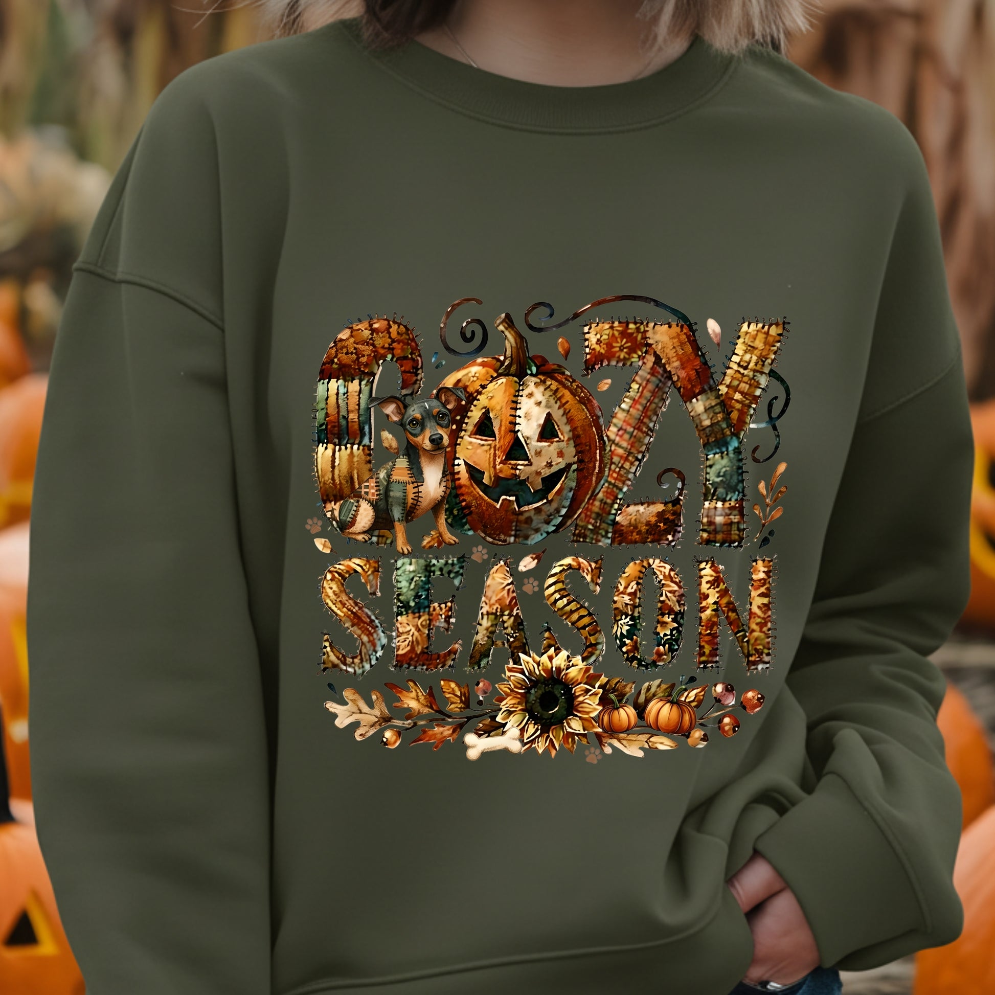 Person wearing a green sweatshirt with 'Happy Halloween' design in front of pumpkins.