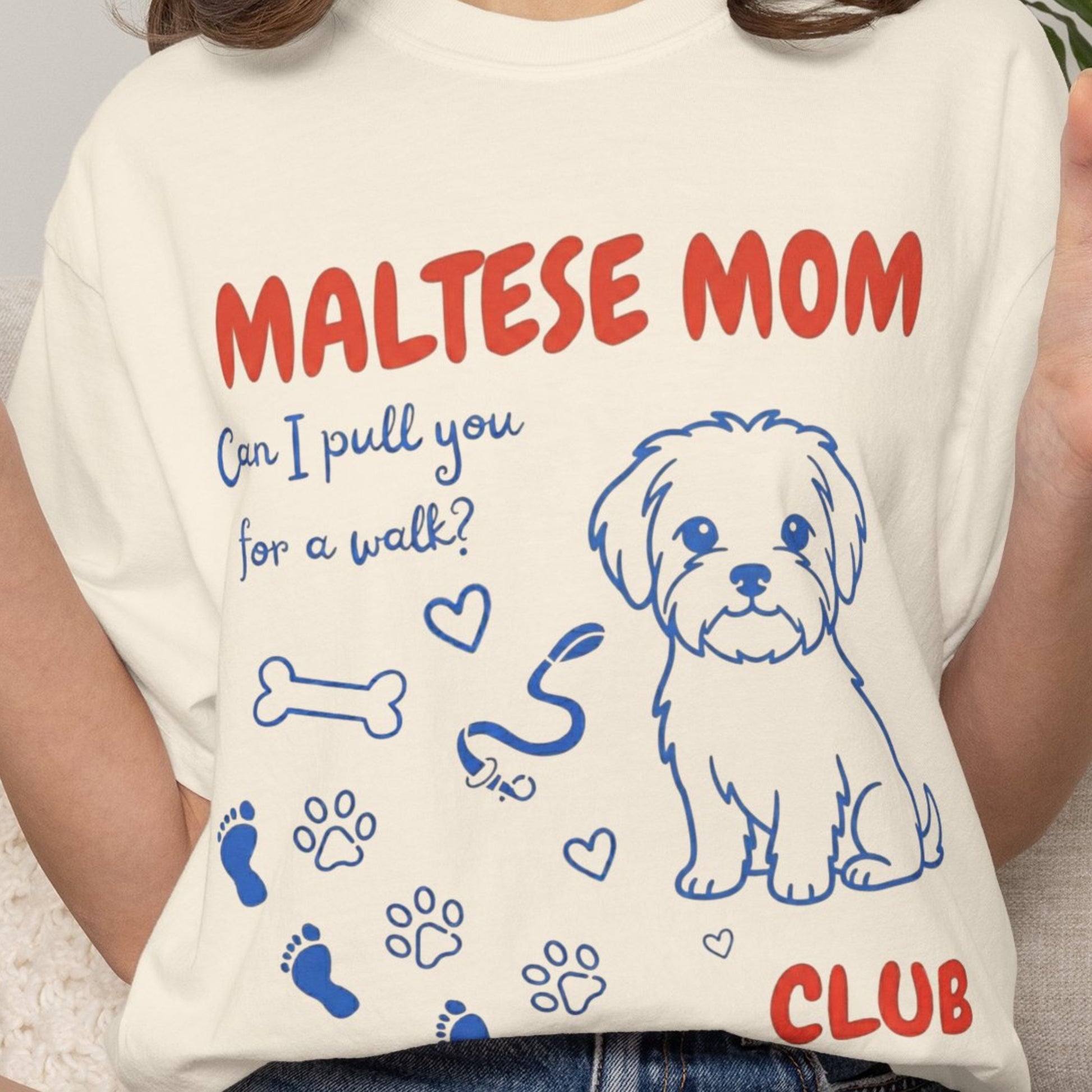 Person wearing a t-shirt with 'Maltese Mom' and dog illustrations.