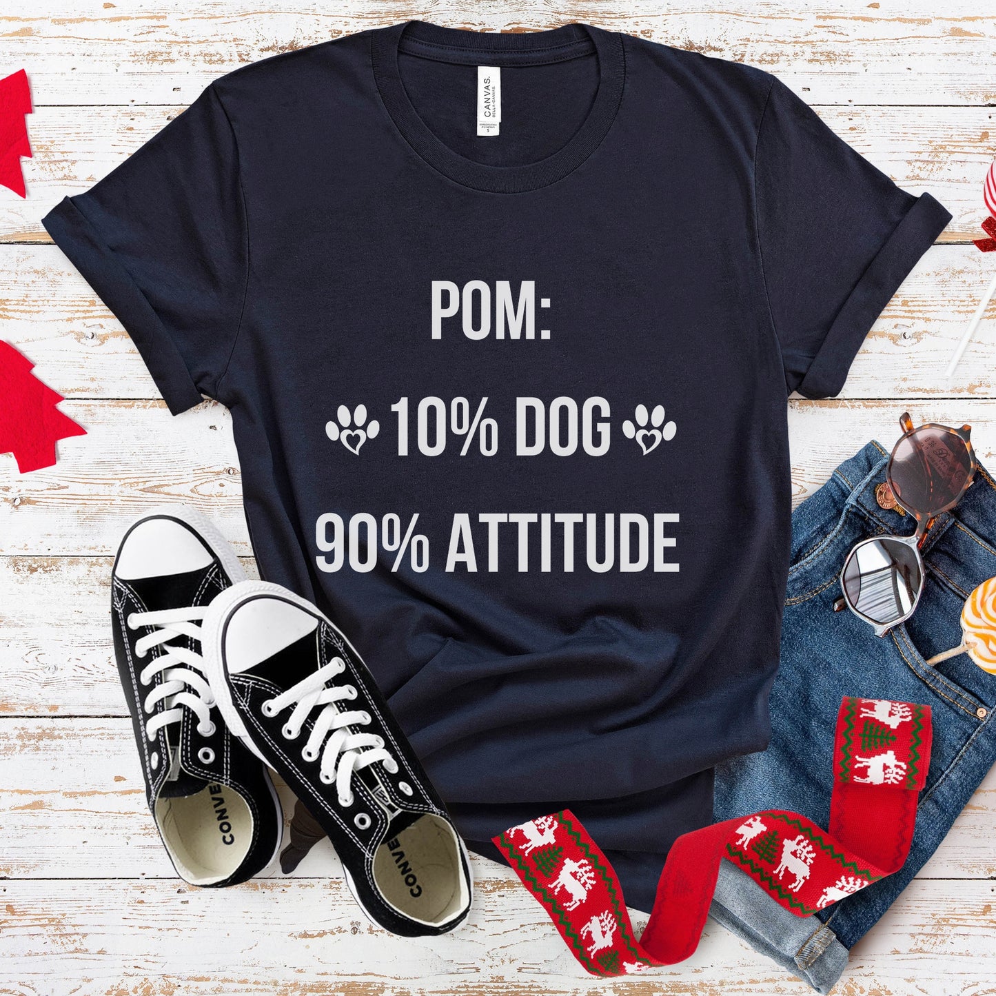 Black t-shirt with humorous text, black sneakers, jeans, and socks on a wooden surface.