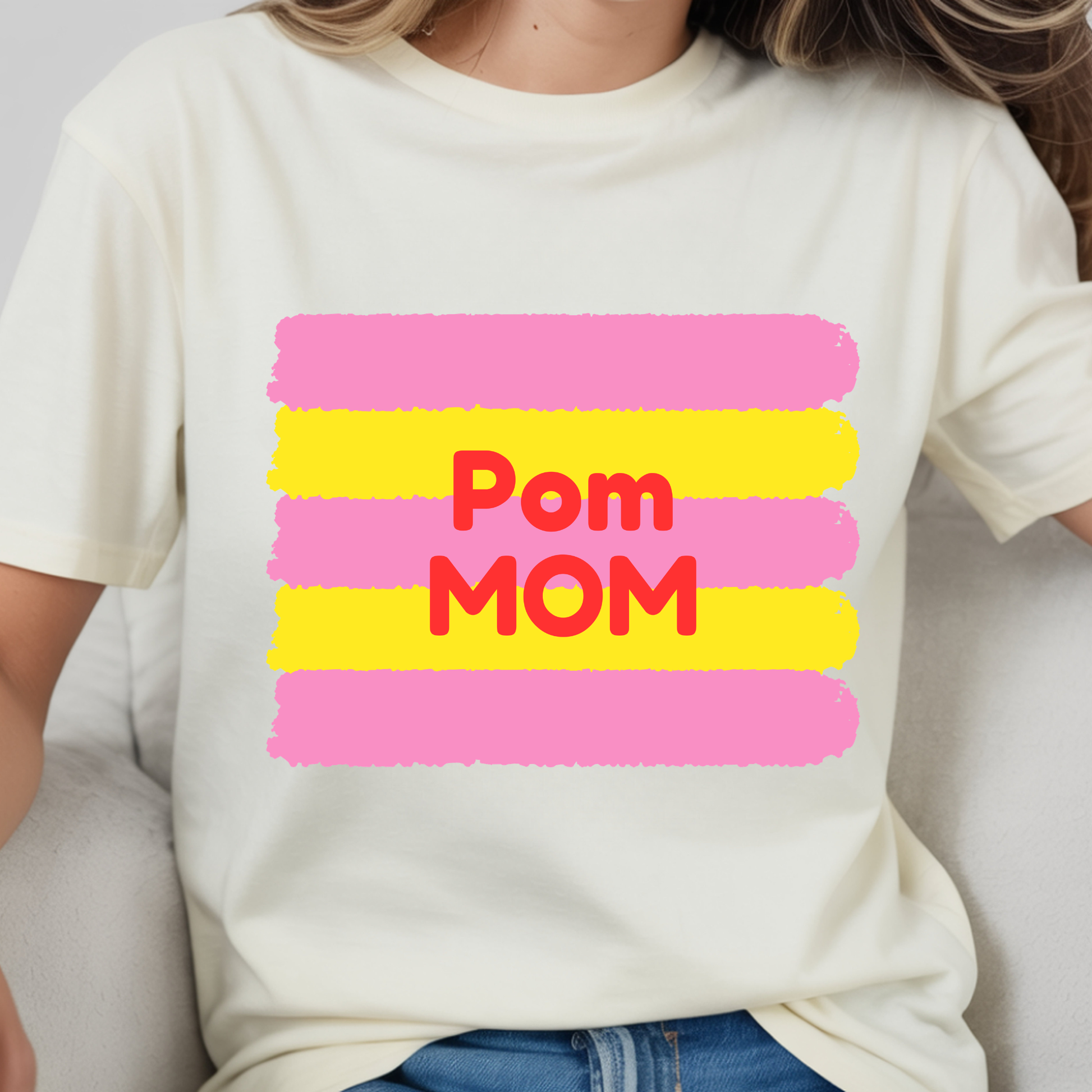 White t-shirt with 'Pom Mom' text in red and pink on a yellow background