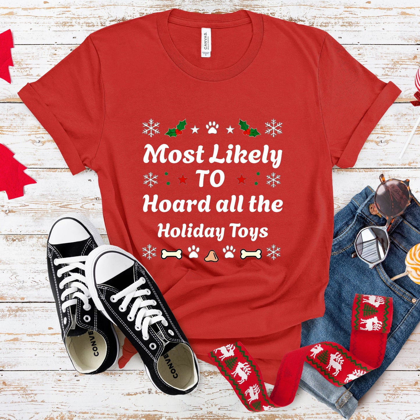 Red t-shirt with humorous text, black sneakers, and festive accessories on a wooden surface.