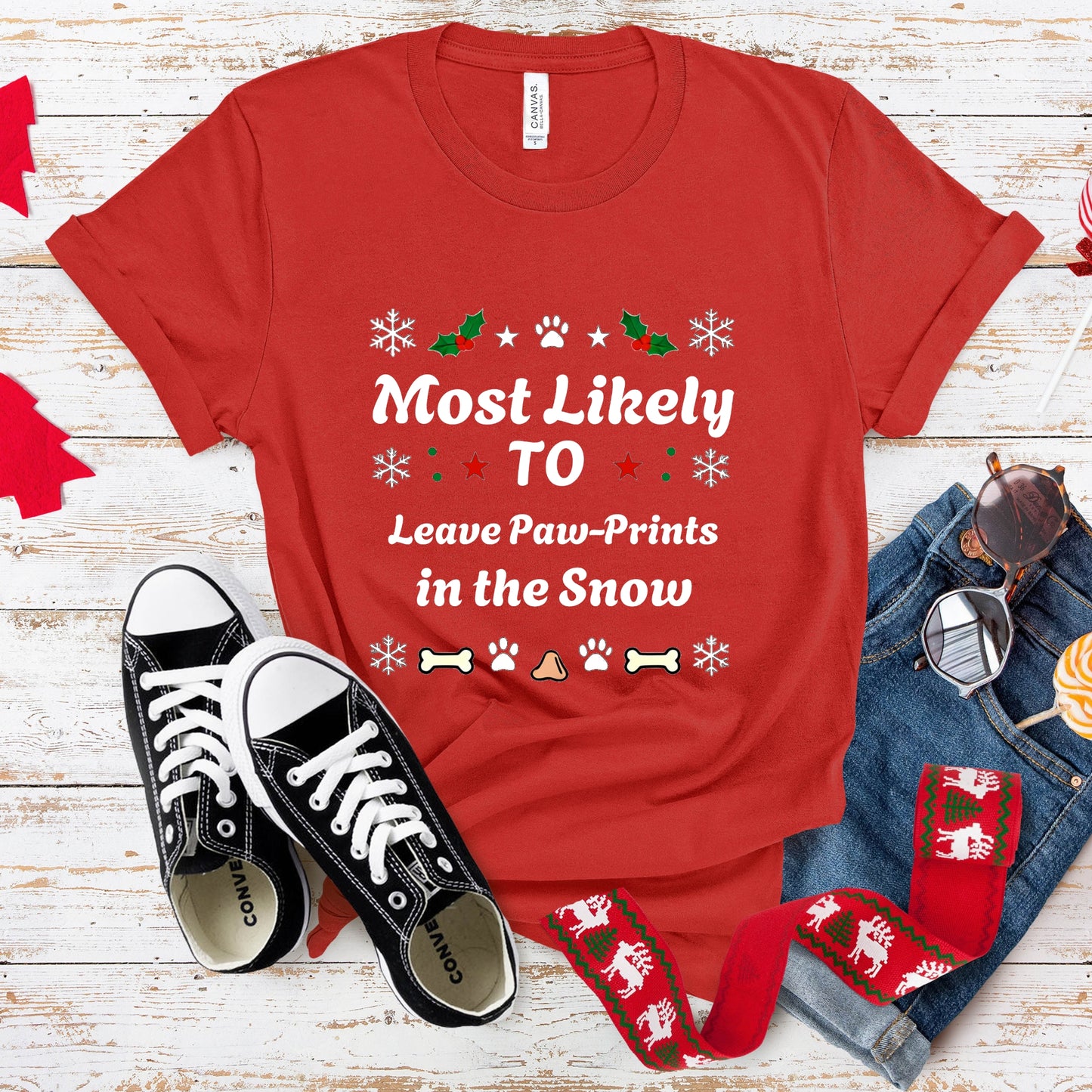 Red t-shirt with humorous text, black sneakers, and festive accessories on a wooden surface