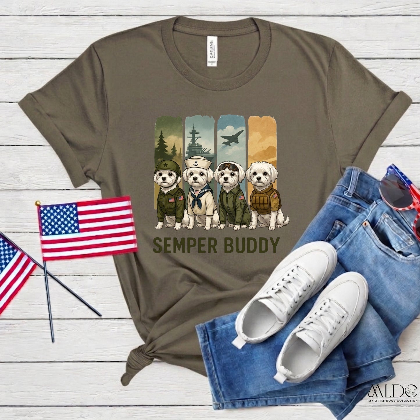 Olive green t-shirt with 'Semper Buddy' design, American flags, jeans, and sneakers on a wooden surface.