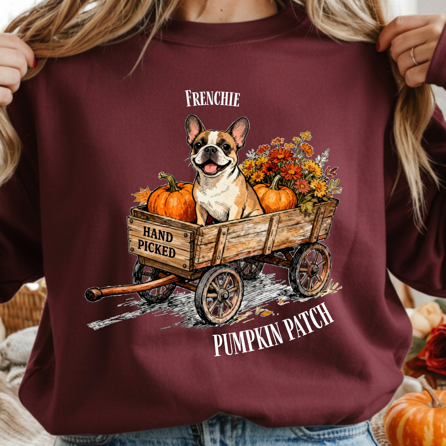 Maroon sweatshirt with a graphic of a French Bulldog in a wagon with pumpkins and flowers, labeled 'Frenchie Hand Picked Pumpkin Patch'.
