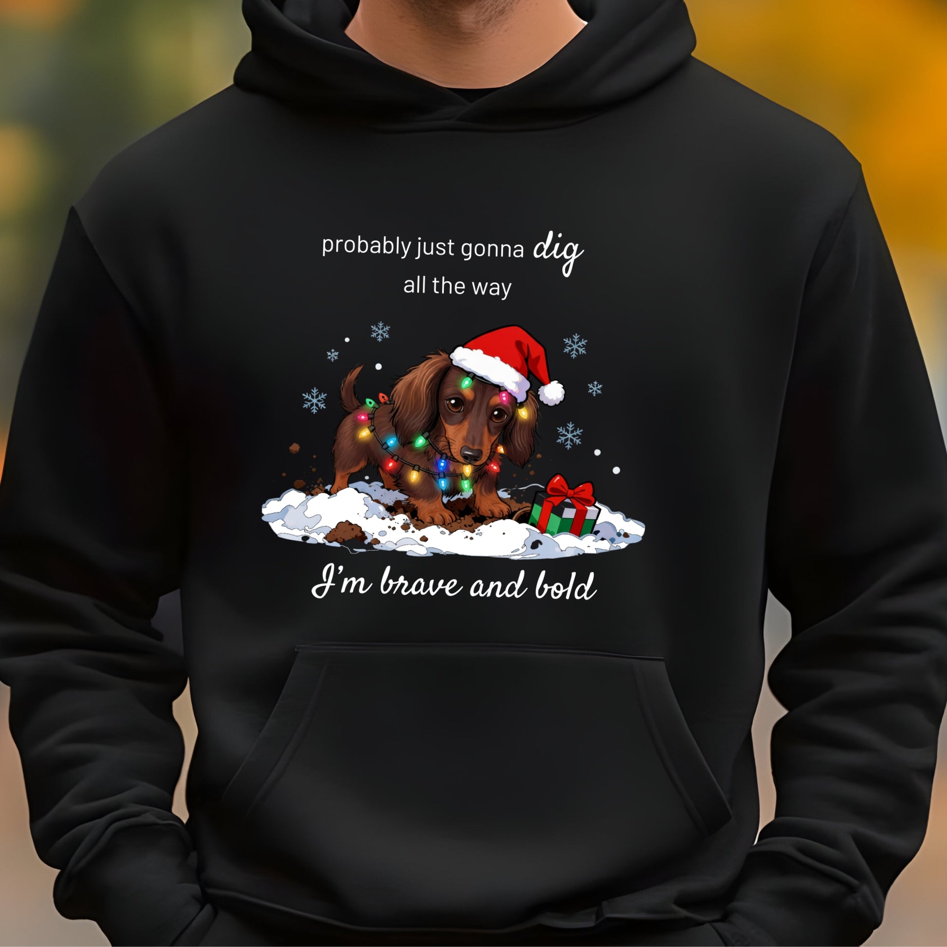 Black hoodie with a Christmas-themed dachshund graphic and text on a blurred background
