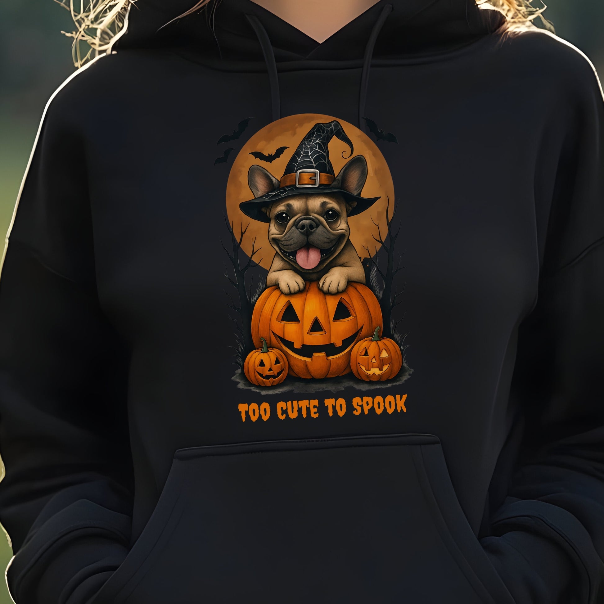 French Bulldog wearing a witch hat with pumpkins and bats, Halloween theme on a black hoodie.