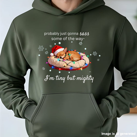 Person wearing a Military Green Chihuahua Christmas hoodie with a sleeping Chihuahua in a Santa hat on Christmas lights and the words probably just gonna sass some of the way, I'm tiny but mighty
