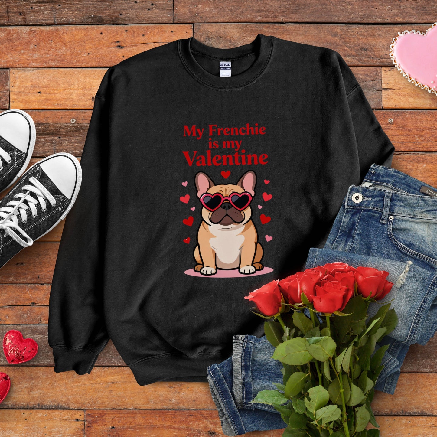 Black sweatshirt with a dog graphic and text on a wooden surface with jeans, roses, and shoes.