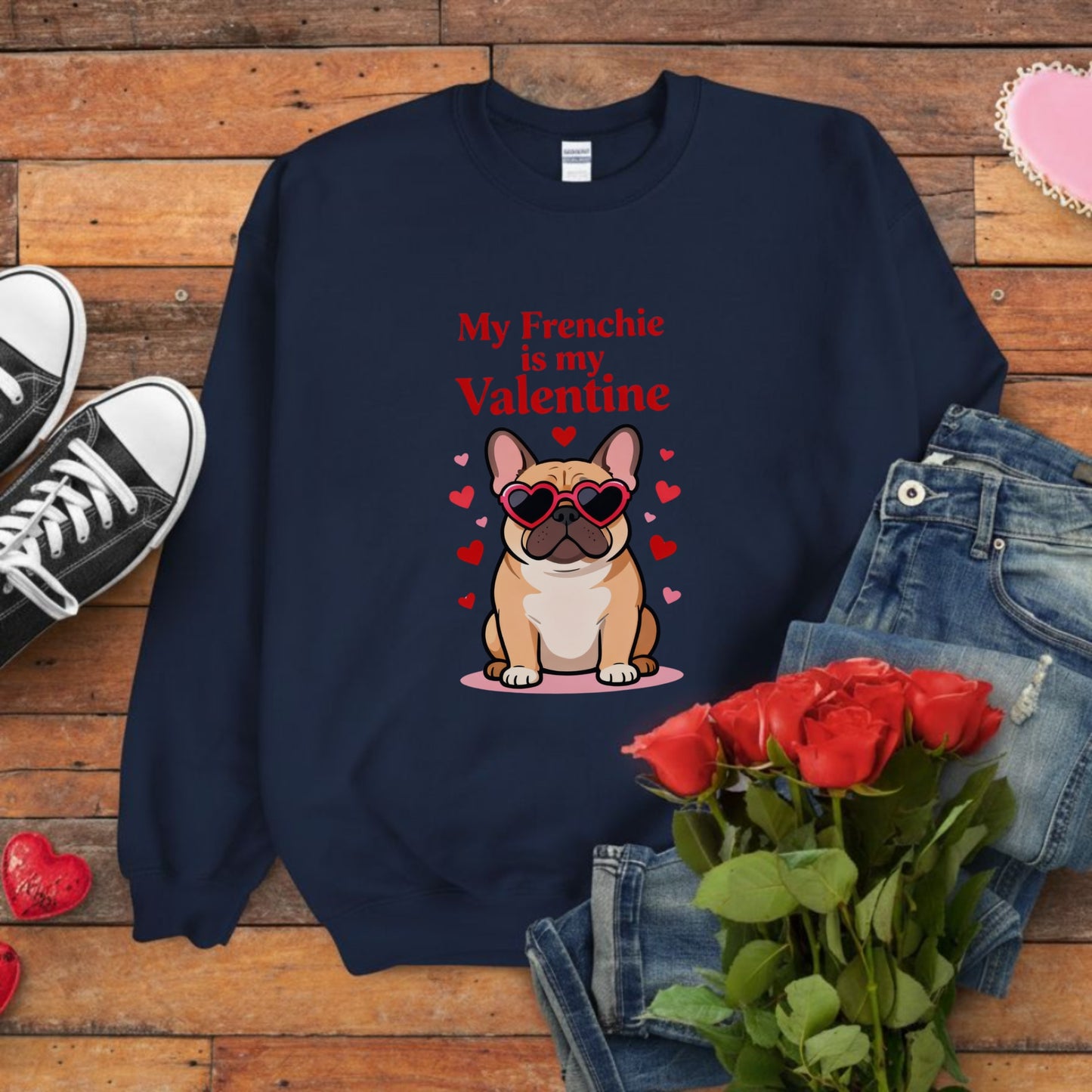 Navy blue sweatshirt with a dog graphic and text on a wooden surface with jeans, shoes, and roses.