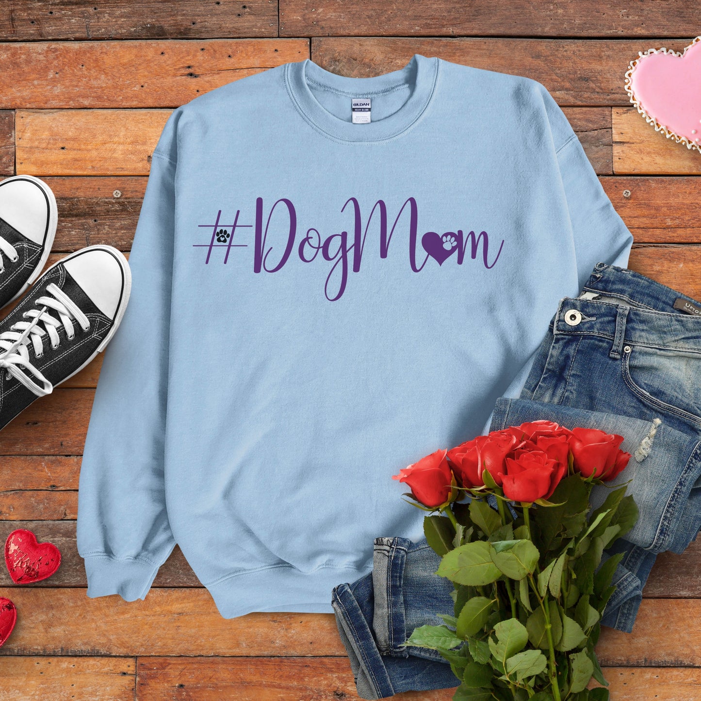 Light blue sweatshirt with '#DogMom' text on a wooden surface with jeans, roses, and shoes.