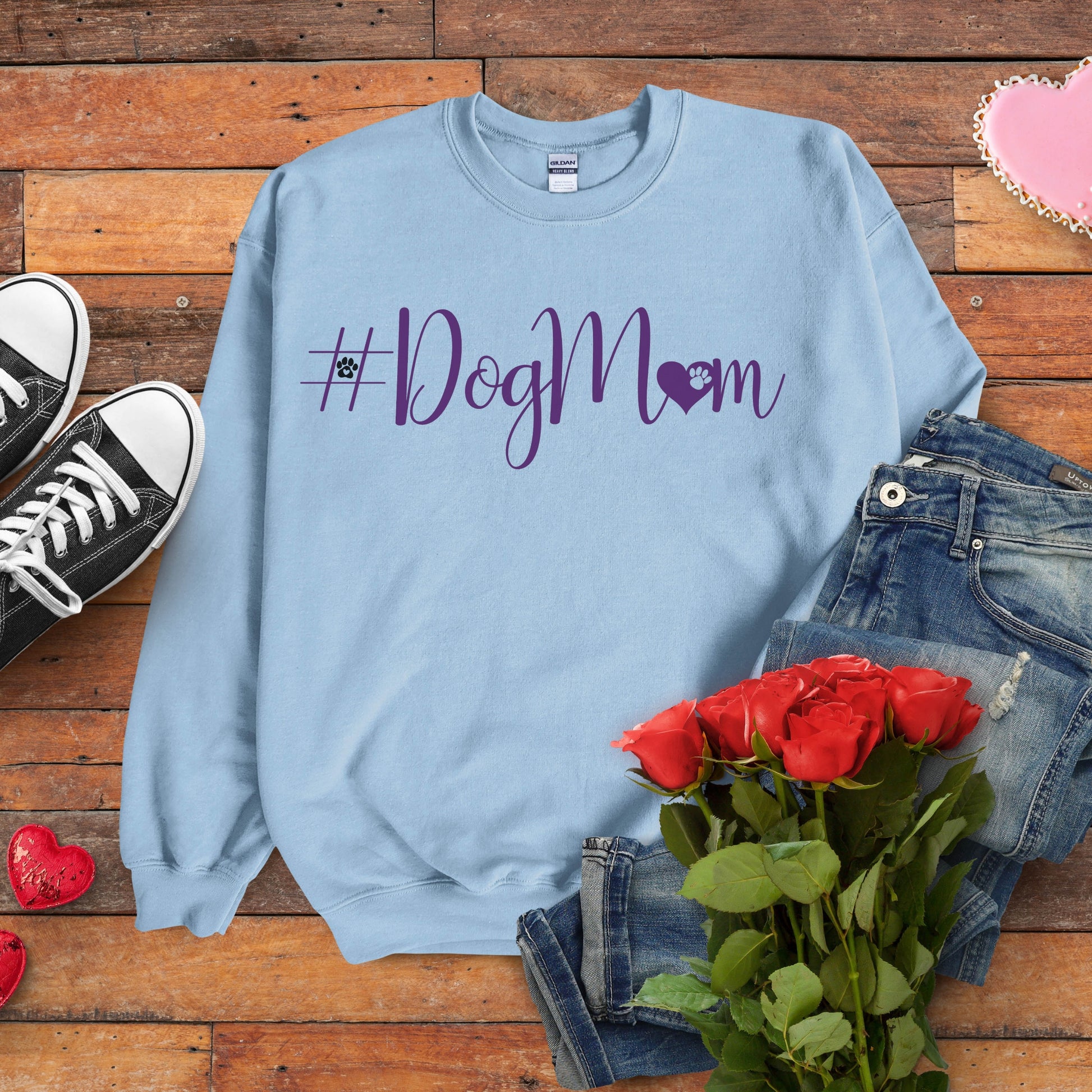 Light blue sweatshirt with '#DogMom' text on a wooden surface with jeans, roses, and shoes.
