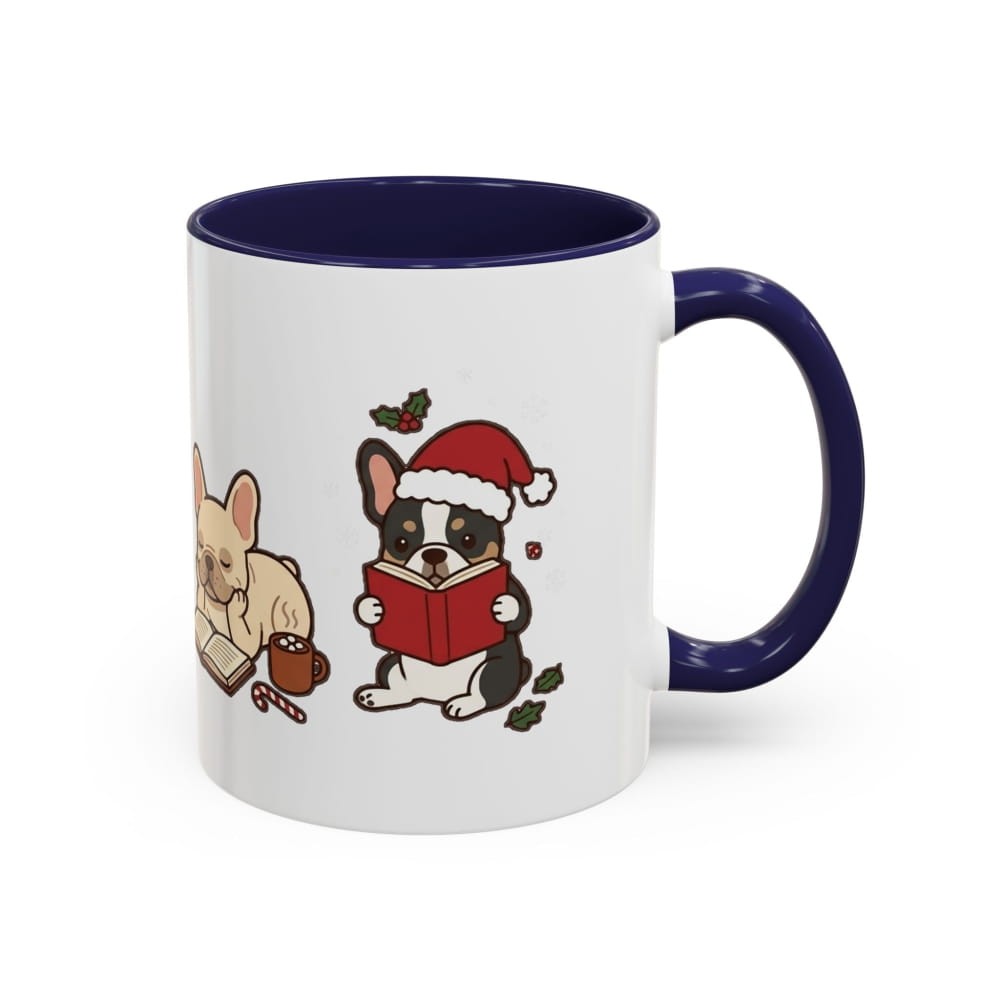 A white ceramic mug with a dark navy blue interior and handle, featuring a cute cartoon illustration of a black and white French Bulldog reading a red Christmas book, next to a beige dog.