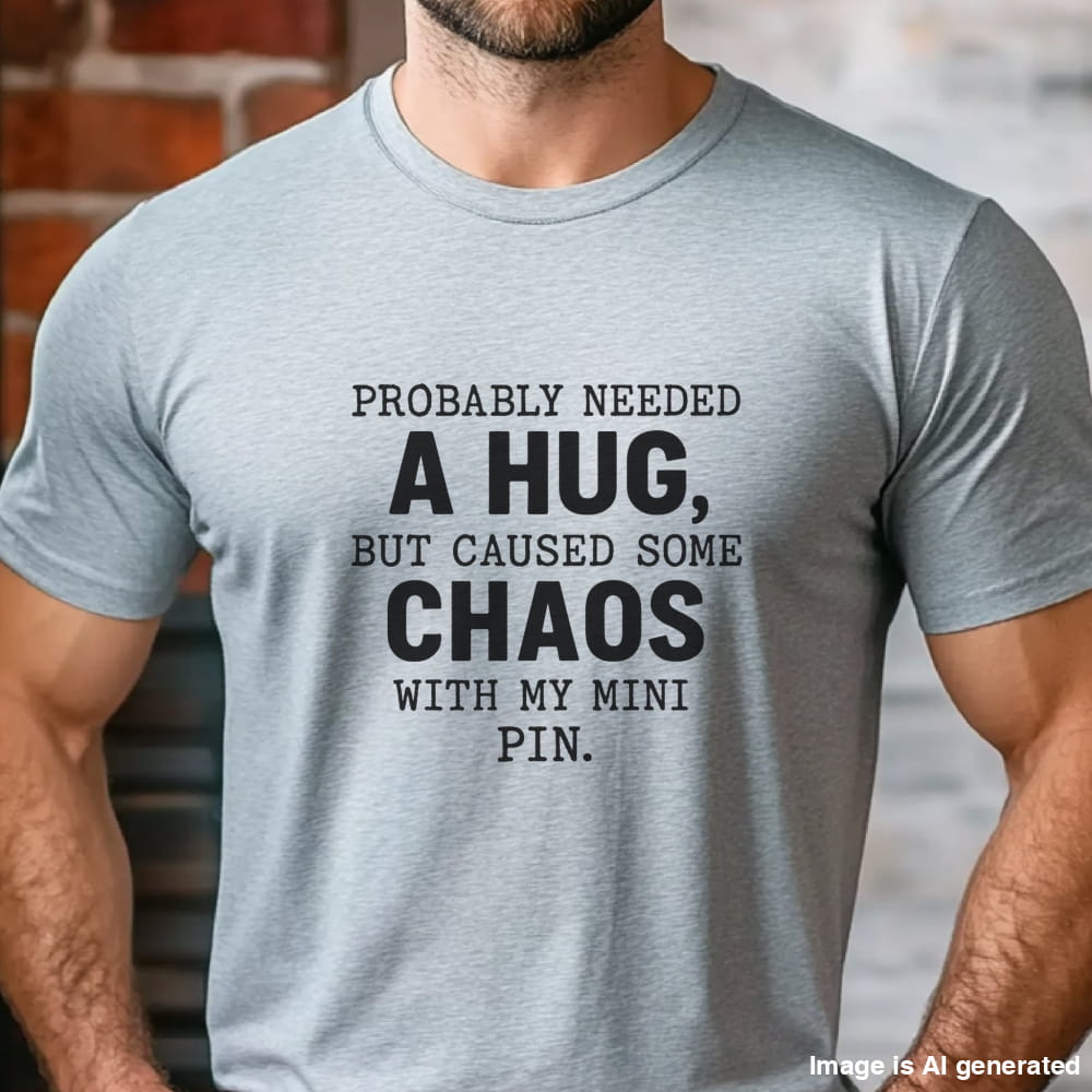 Grey unisex t-shirt with white text: "Probably needed a hug, but caused some chaos with my Mini Pin." centered on the chest
