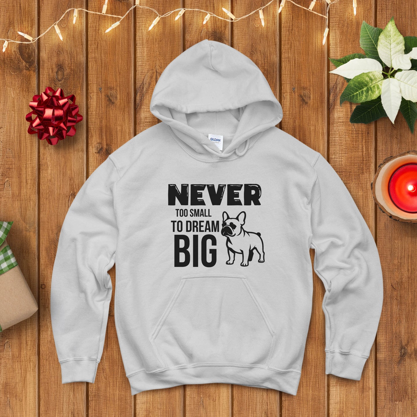 Gray hoodie with motivational quote and dog illustration on a wooden surface with festive decorations.