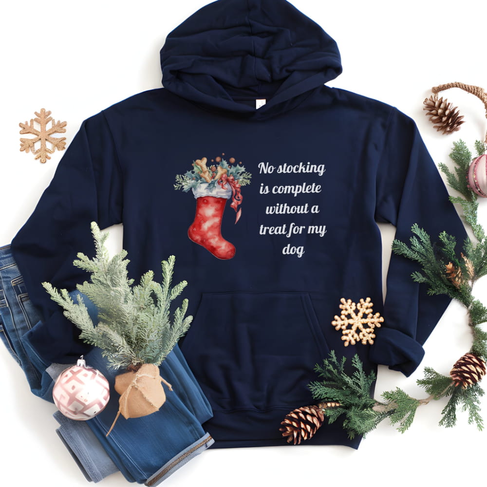 Navy blue hoodie with Christmas stocking design and text, surrounded by holiday decorations on a white background.