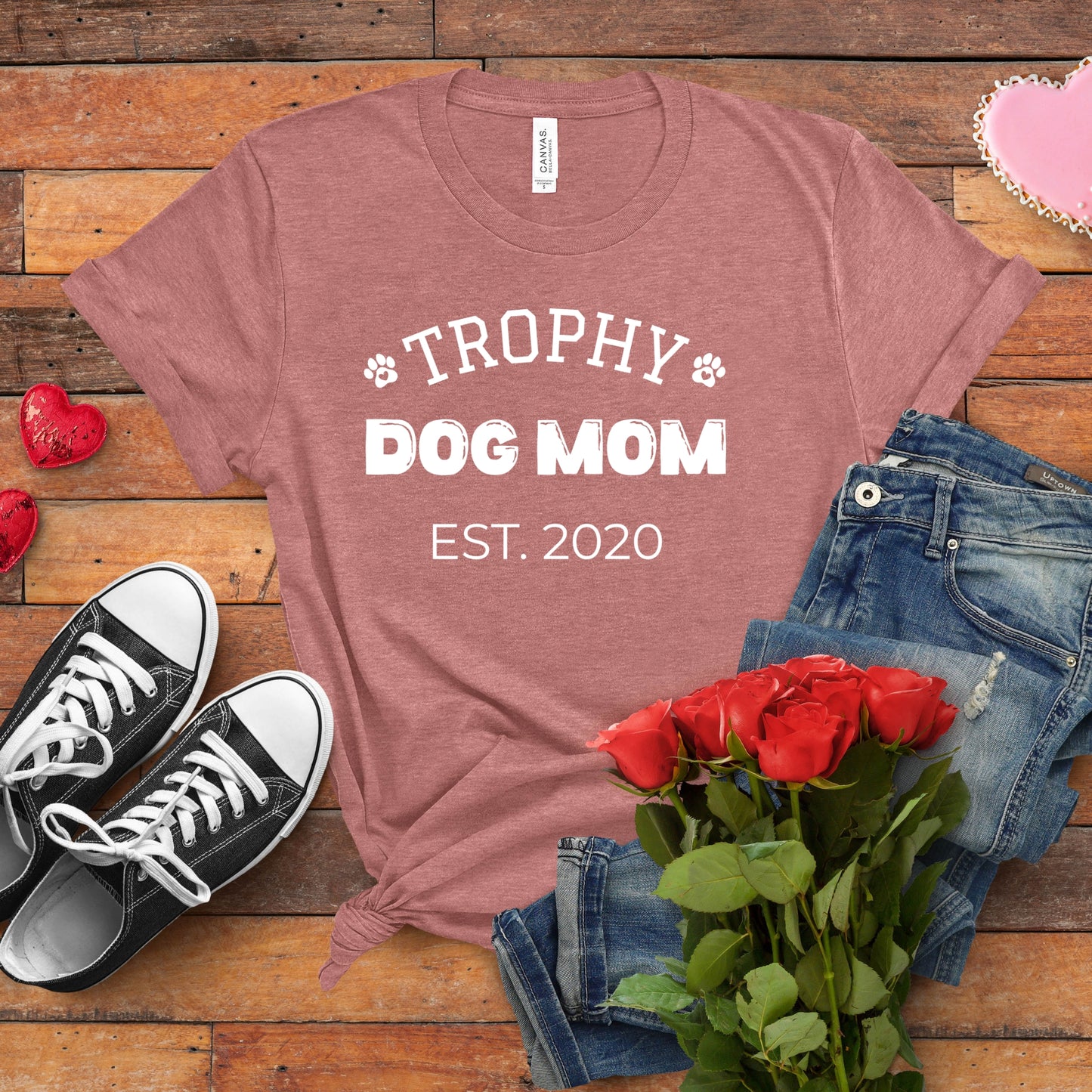 T-shirt with 'Trophy Dog Mom Est. 2020' text on a wooden surface with shoes, jeans, and roses.
