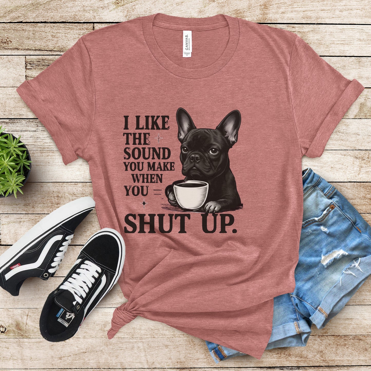 Red t-shirt with a dog graphic and text, paired with sneakers and jeans on a wooden surface