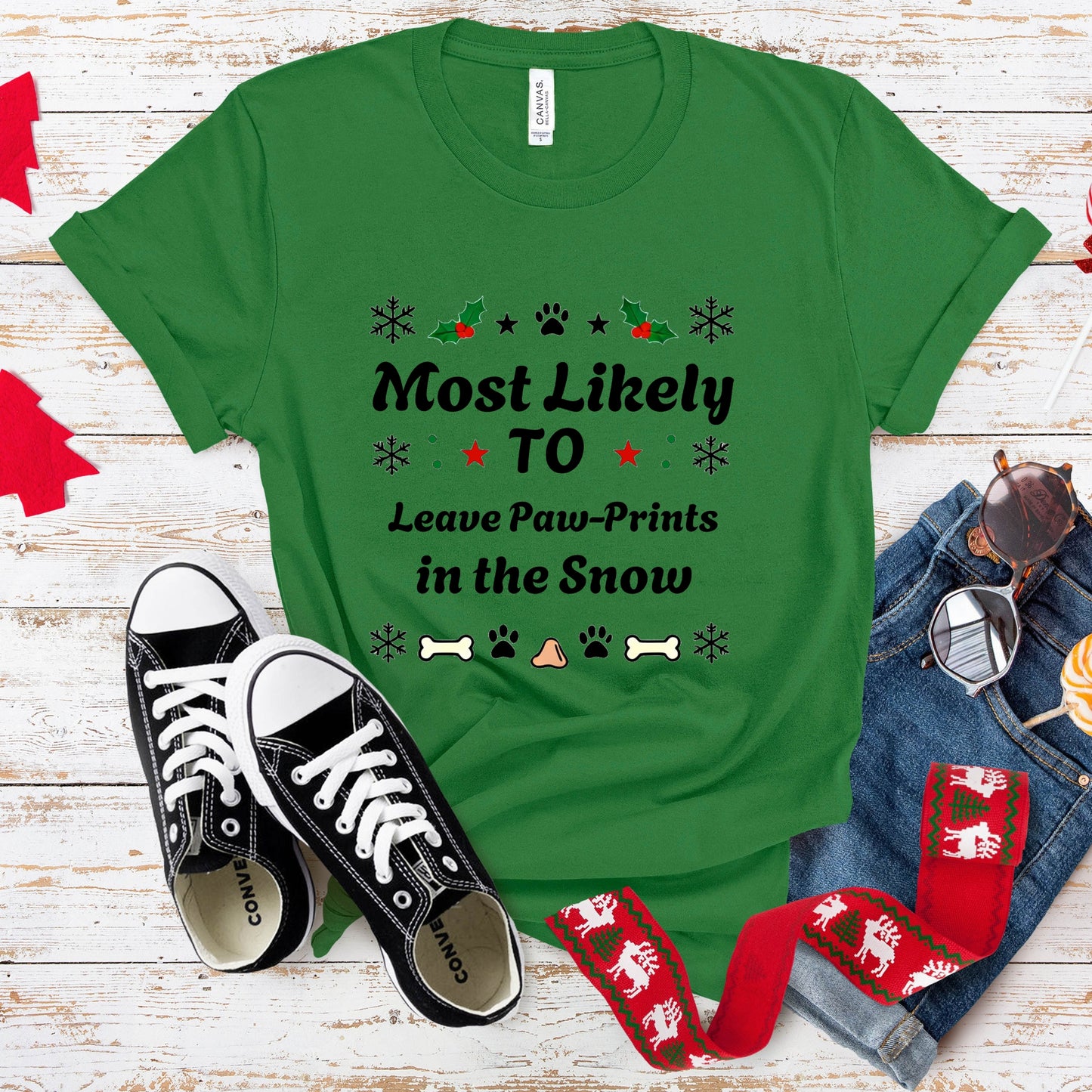 Green t-shirt with dog-themed text, black sneakers, and Christmas-themed socks on a wooden surface.