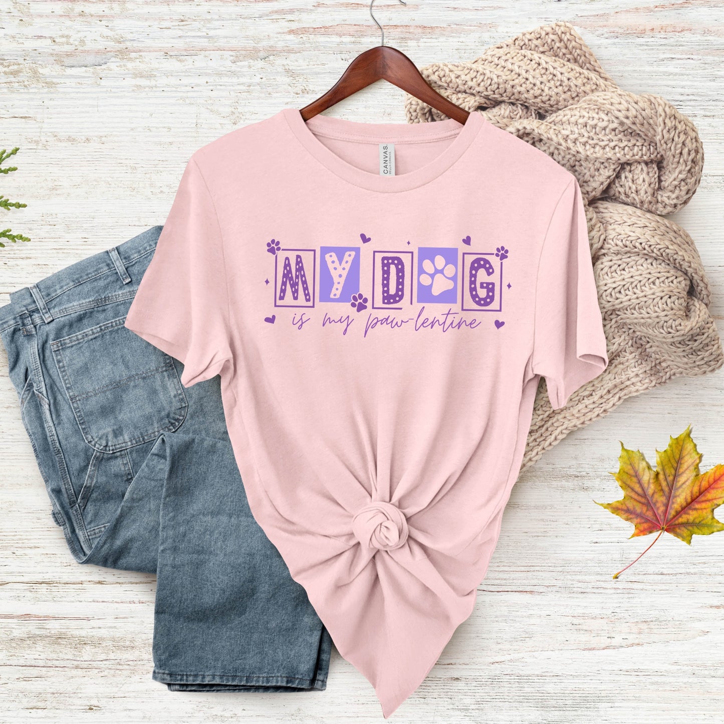 Pink t-shirt with 'My Dog is my Valentine' text on a wooden surface with jeans and a sweater.