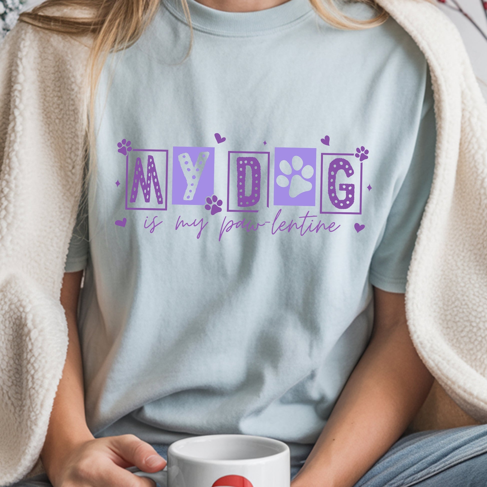 Person wearing a light blue t-shirt with 'MY DOG is my paw-lentine' text, holding a mug.