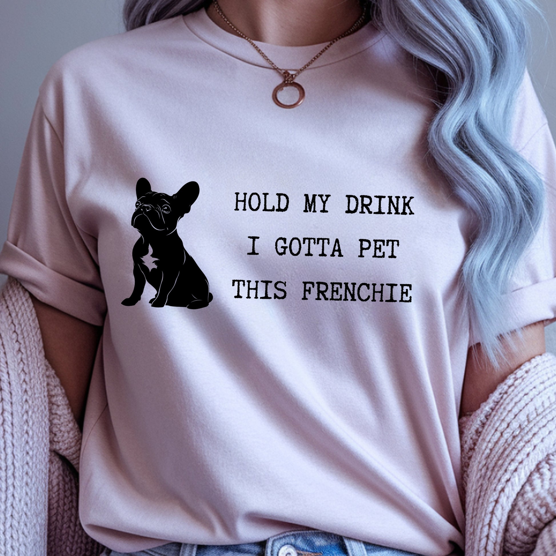 Person wearing a pink t-shirt with a dog graphic and text, sitting on a textured surface.