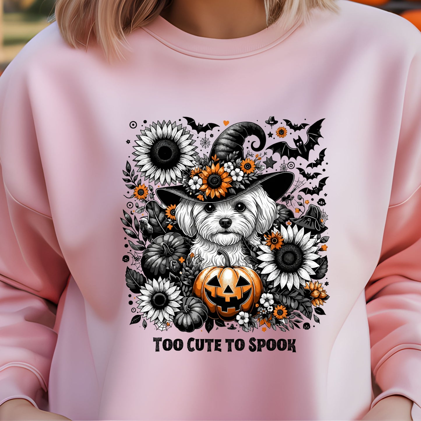 Pink sweatshirt with a Halloween-themed design featuring a dog in a witch hat and pumpkins.