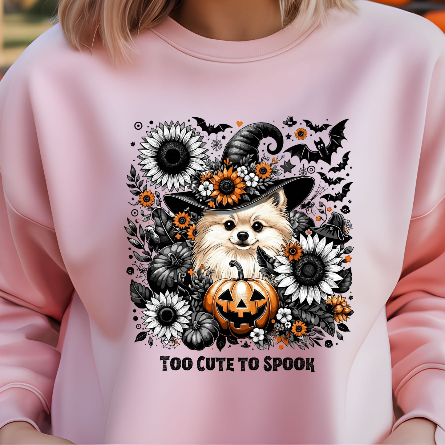 Pink sweatshirt with a Halloween-themed design featuring a dog in a witch hat and pumpkins.