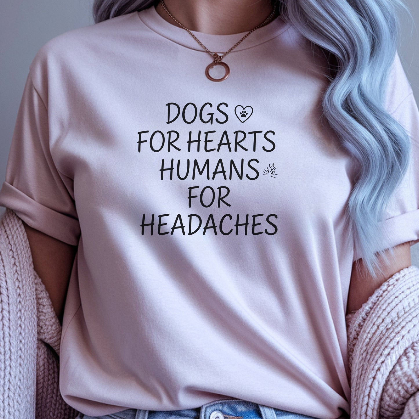 Person wearing a light pink t-shirt with text 'DOGS FOR HEARTS HUMANS FOR HEADACHES' against a neutral background.