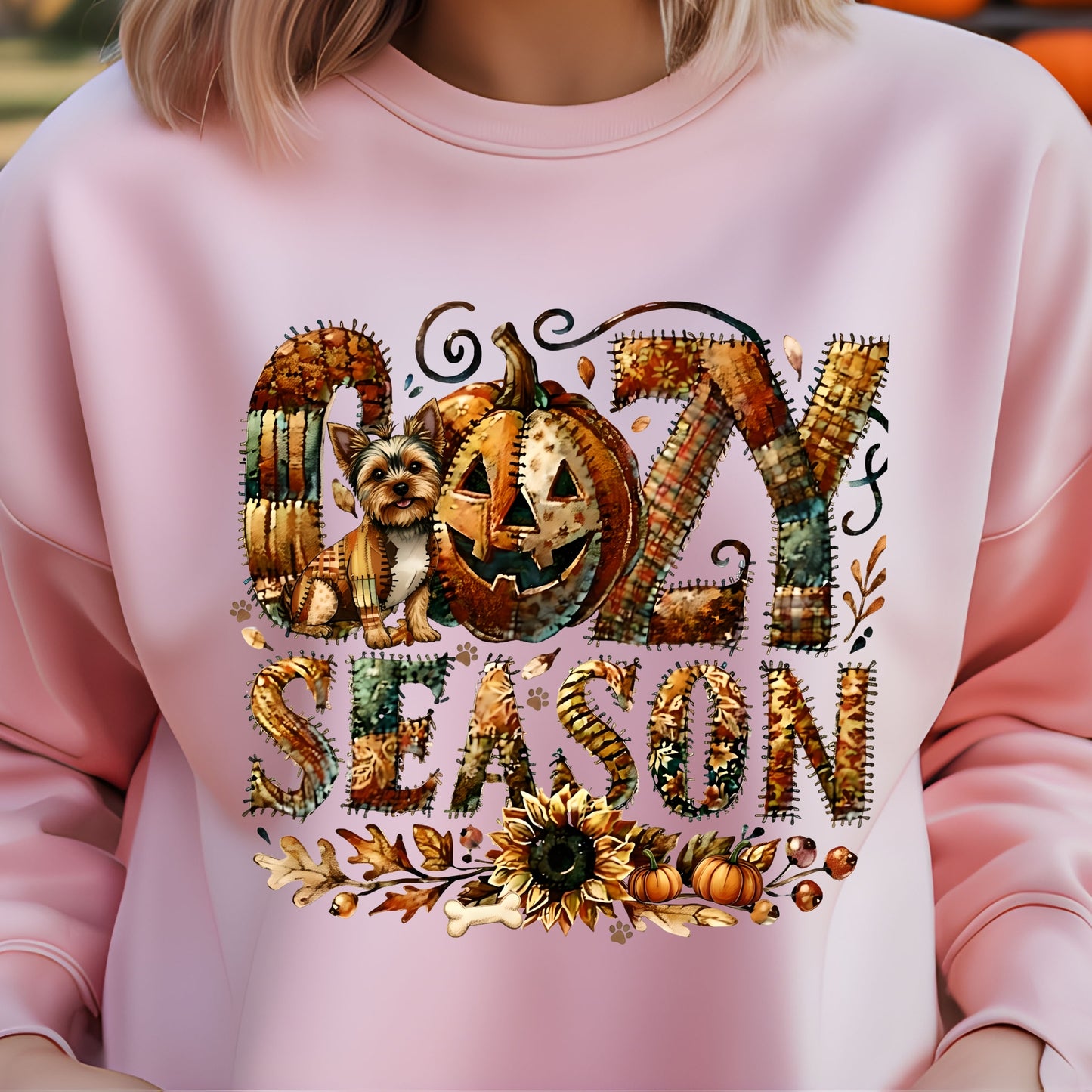 Pink sweatshirt with ' cozy season' design featuring pumpkins and a dog.
