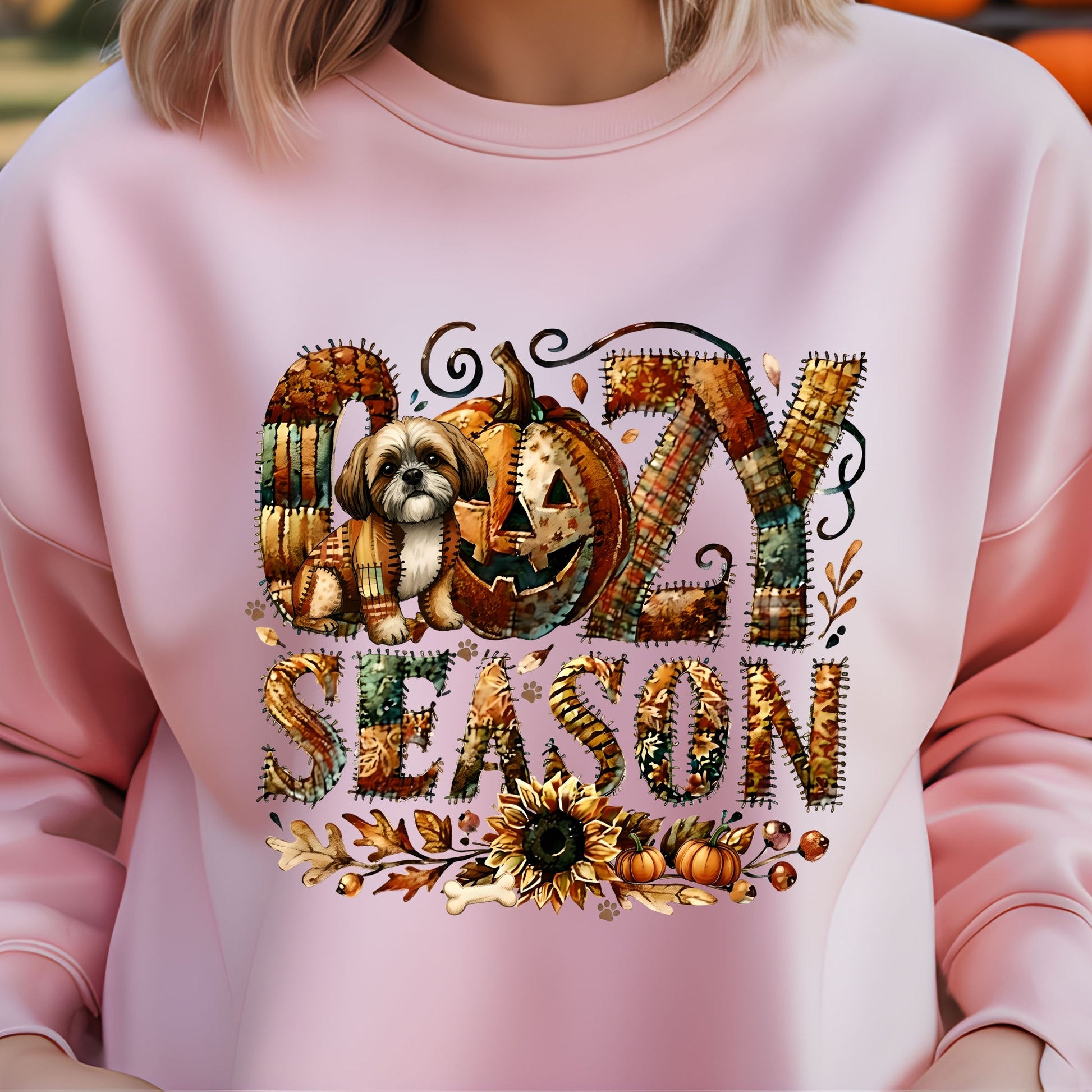 Pink sweatshirt with 'Ozzy Season' design featuring a pumpkin and dog, on a blurred background.