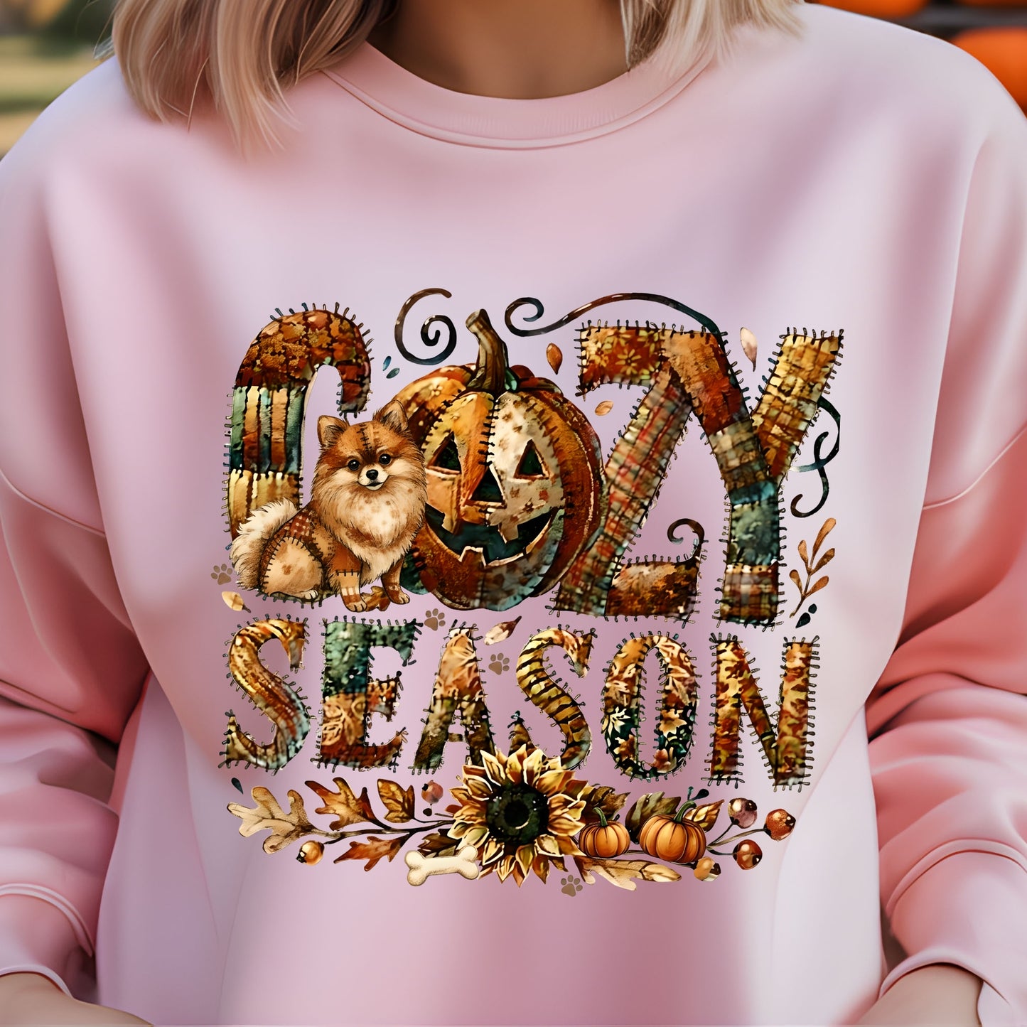 Pink sweatshirt with ' cozy season' design featuring a dog, pumpkin, and autumn elements.