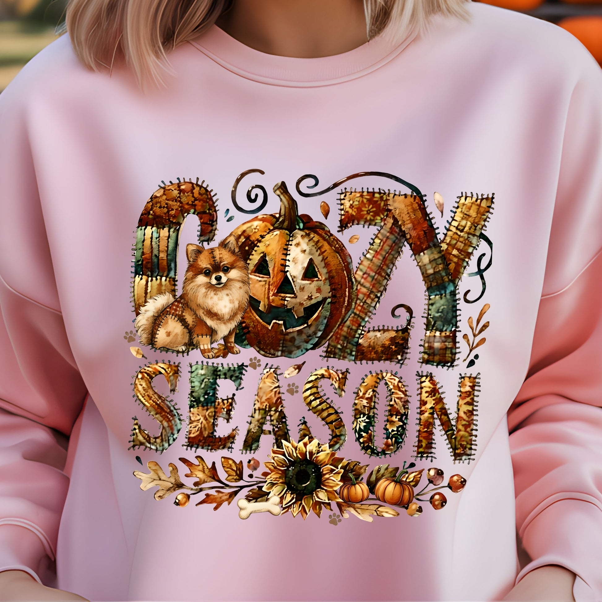 Pink sweatshirt with ' cozy season' design featuring a dog, pumpkin, and autumn elements.