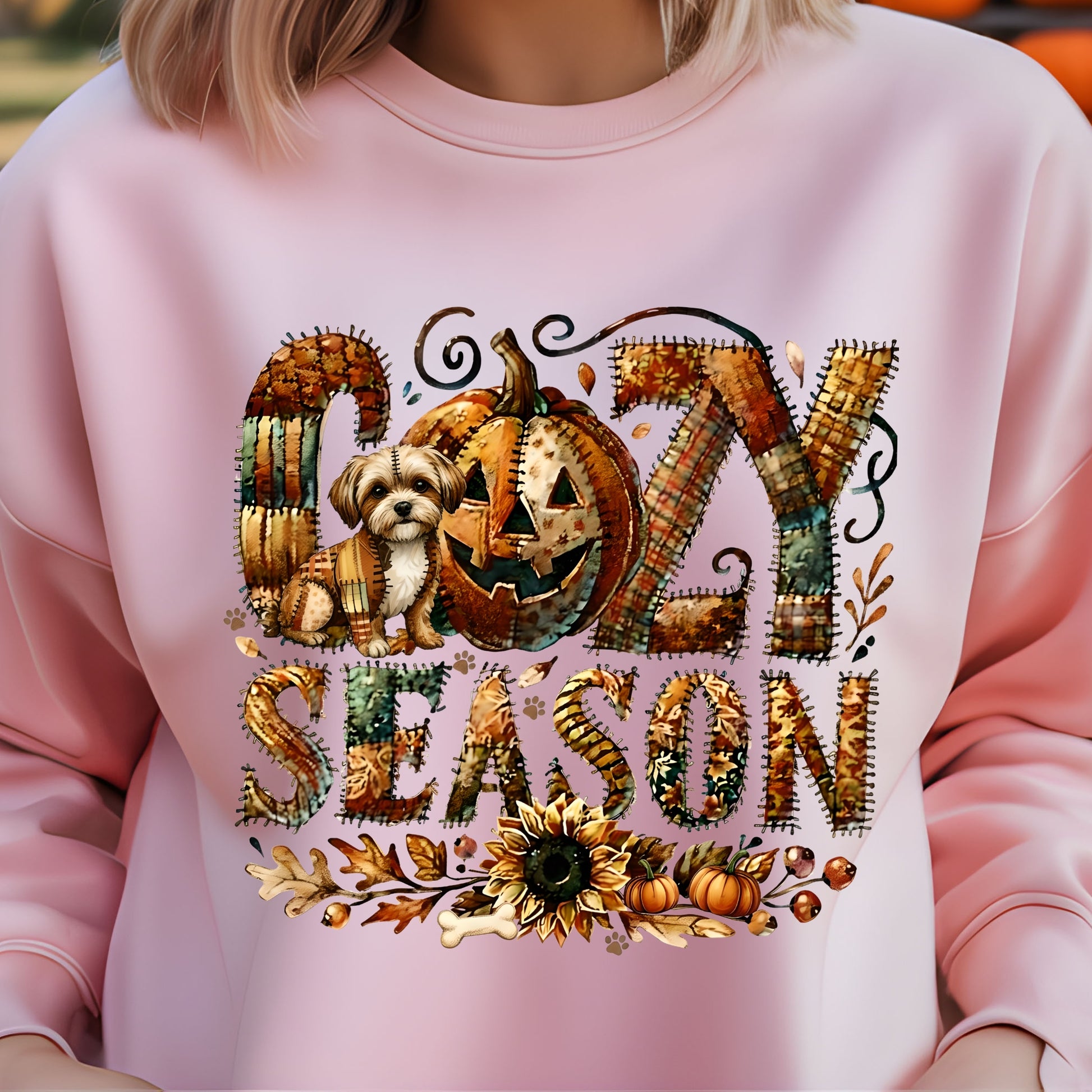 Pink sweatshirt with ' cozy season' design featuring pumpkins and a dog.