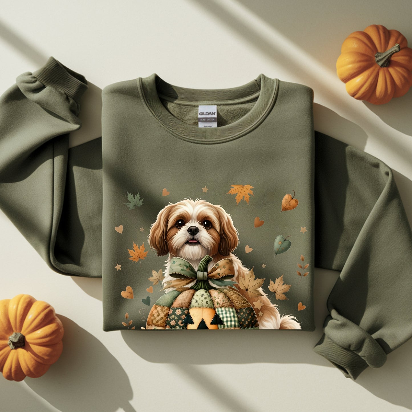 Green sweatshirt with a dog and autumn leaves design, surrounded by pumpkins on a light background