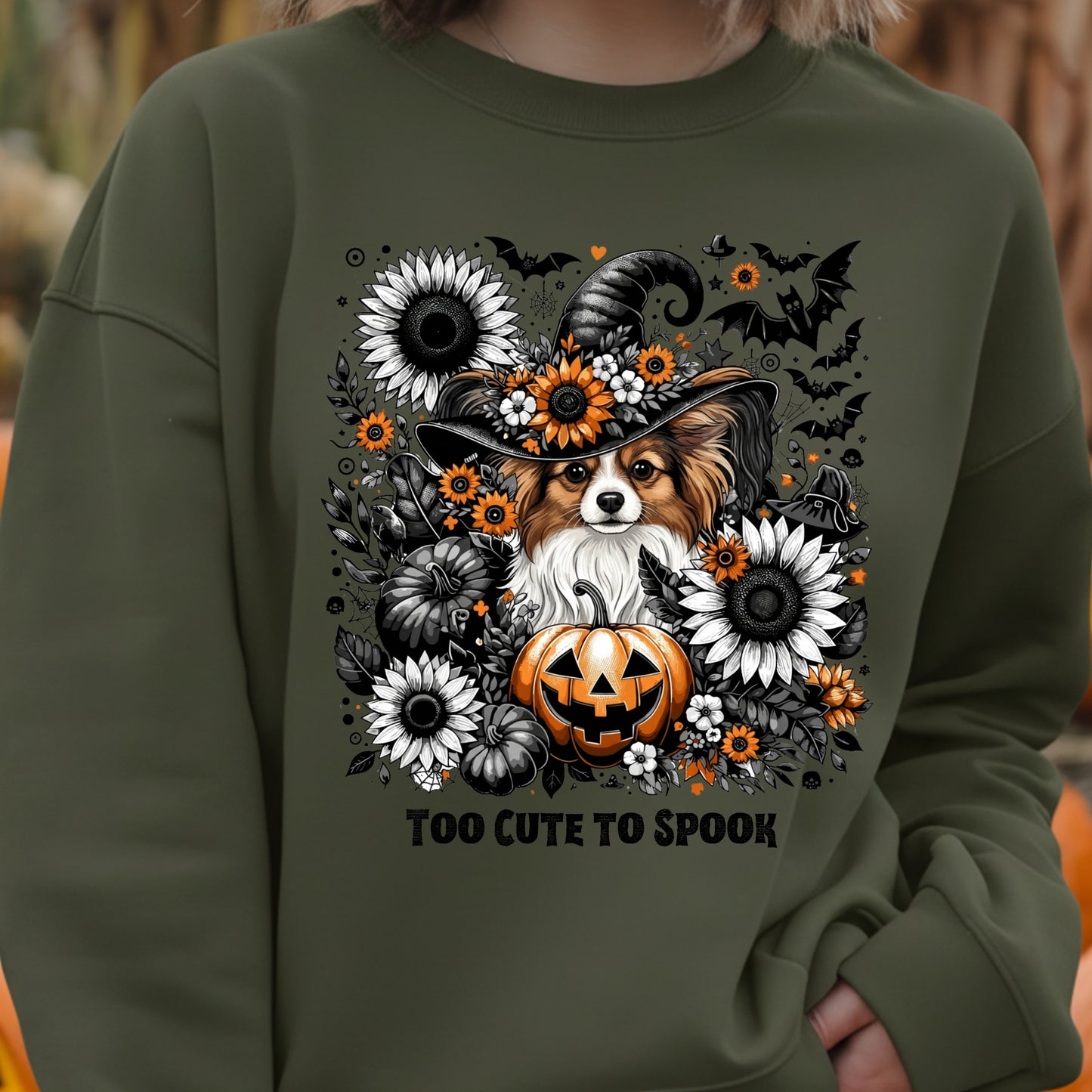Green sweatshirt with a Halloween-themed design featuring a dog in a witch hat, pumpkins, and flowers.