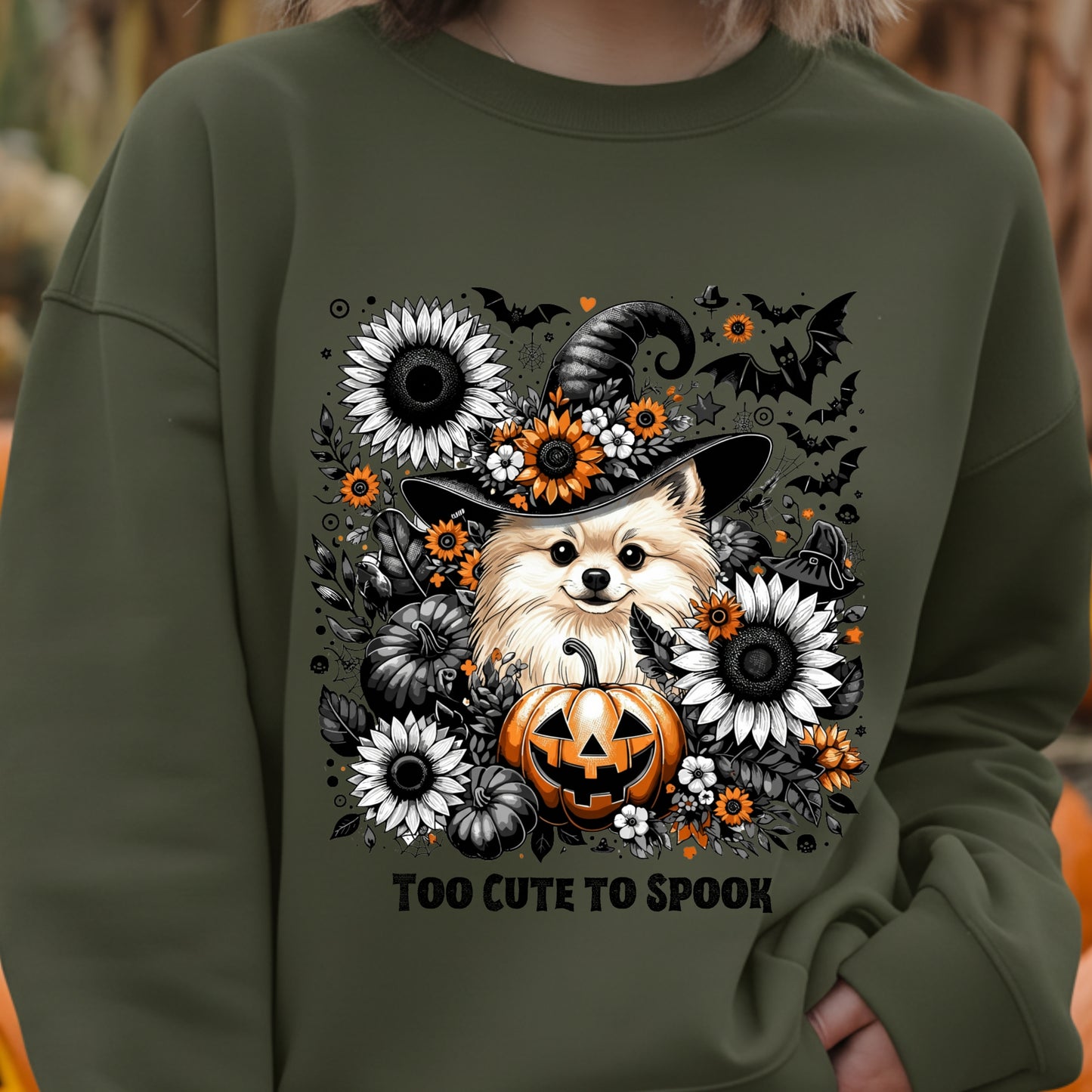 Green sweatshirt with a Halloween-themed design featuring a dog in a witch hat, pumpkins, and flowers.