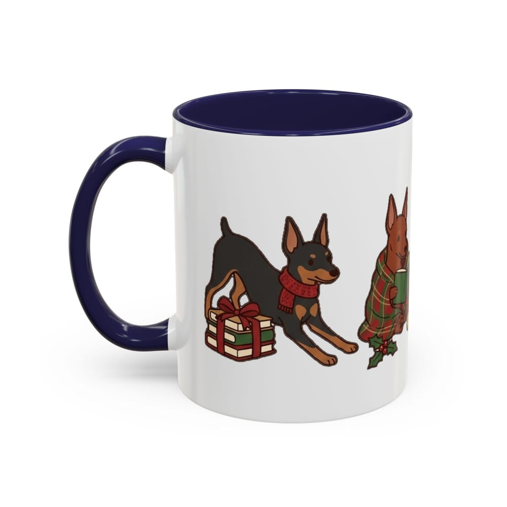 White ceramic mug with a navy interior and navy handle, showing a Mini Pinscher leaning over a wrapped gift and another in a plaid blanket.