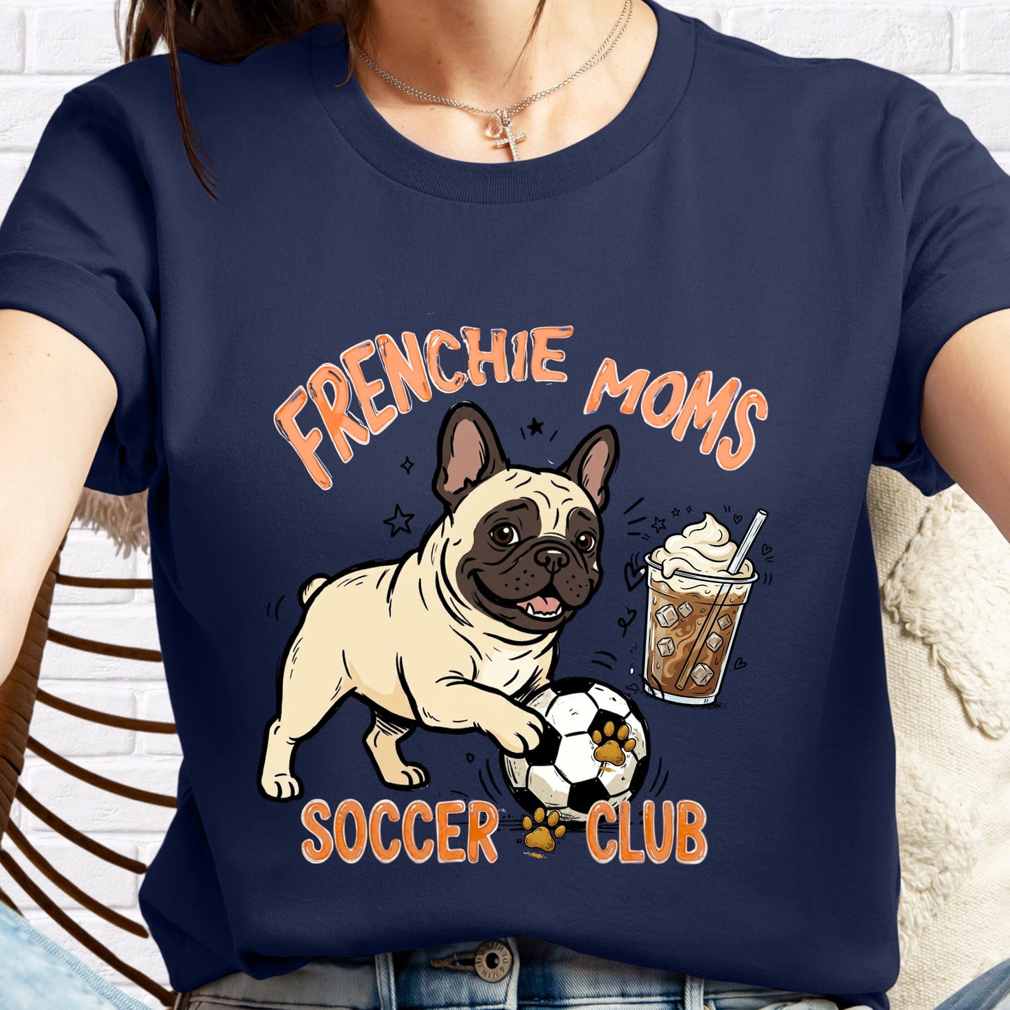 Navy blue t-shirt with a graphic of a French Bulldog, soccer ball, and iced coffee, text 'FRENCHIE MOMS SOCCER CLUB'.