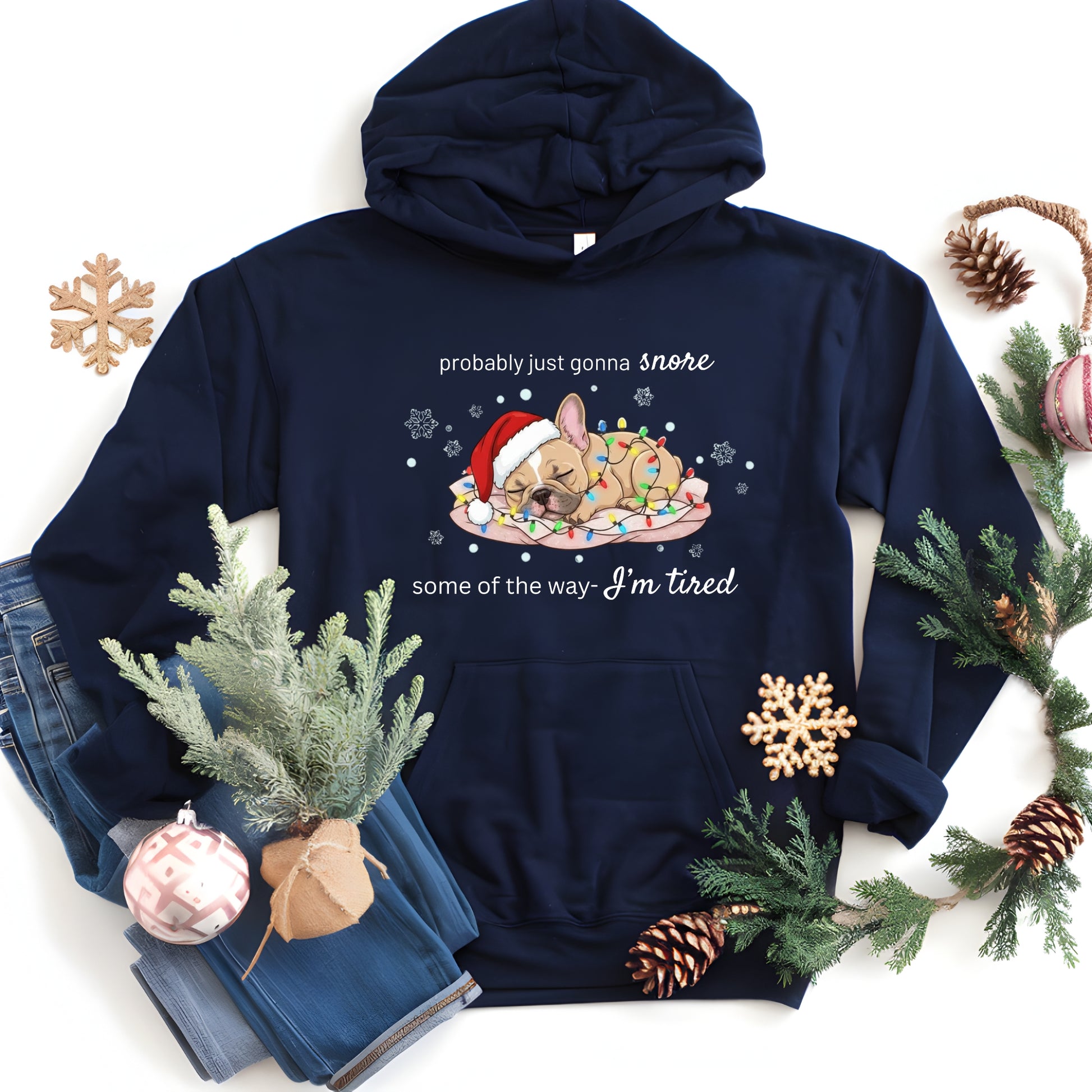 Navy blue hoodie with a Christmas-themed design featuring a dog and text, surrounded by holiday decorations on a white background.