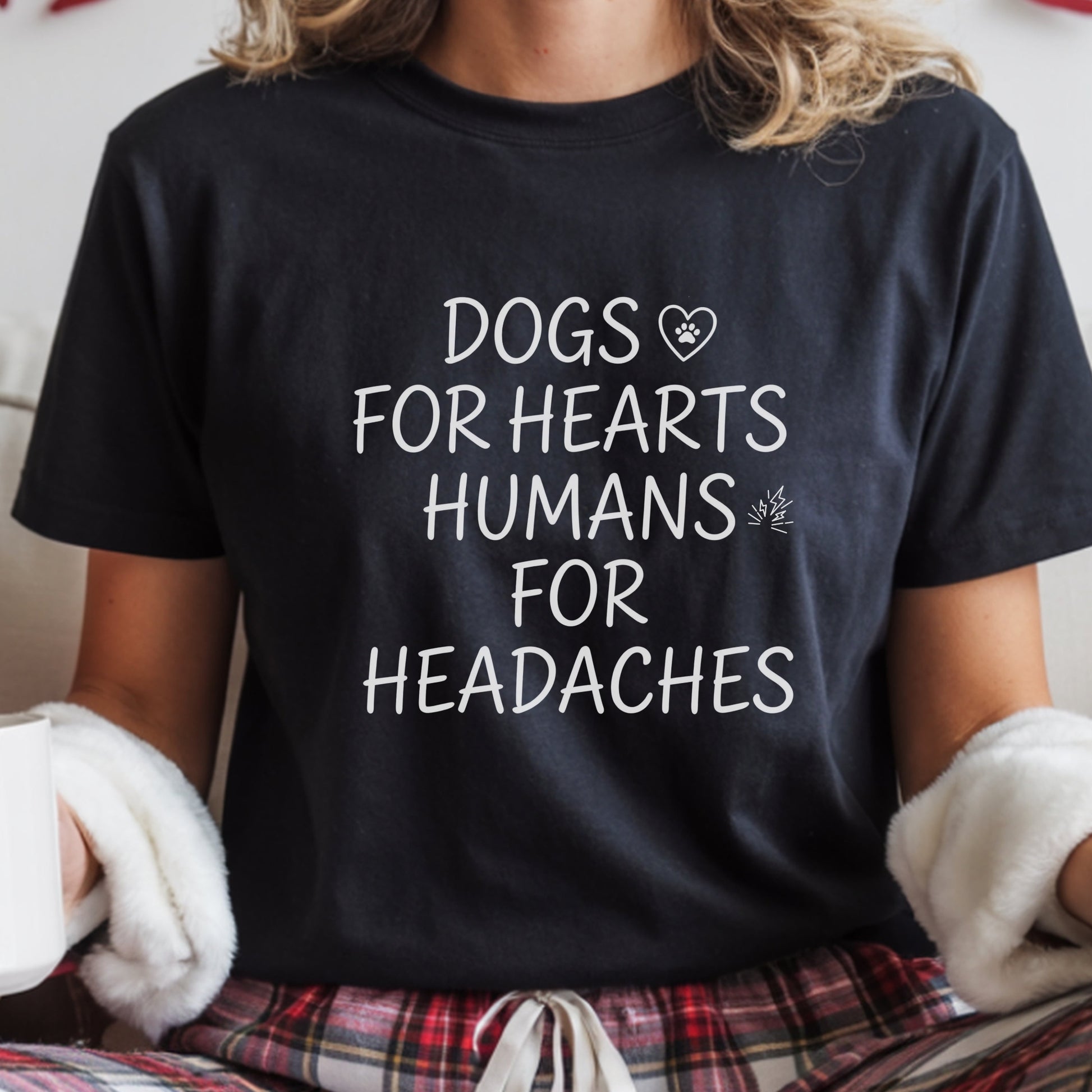 Person wearing a black t-shirt with text 'DOGS FOR HEARTS HUMANS FOR HEADACHES' in a casual setting.