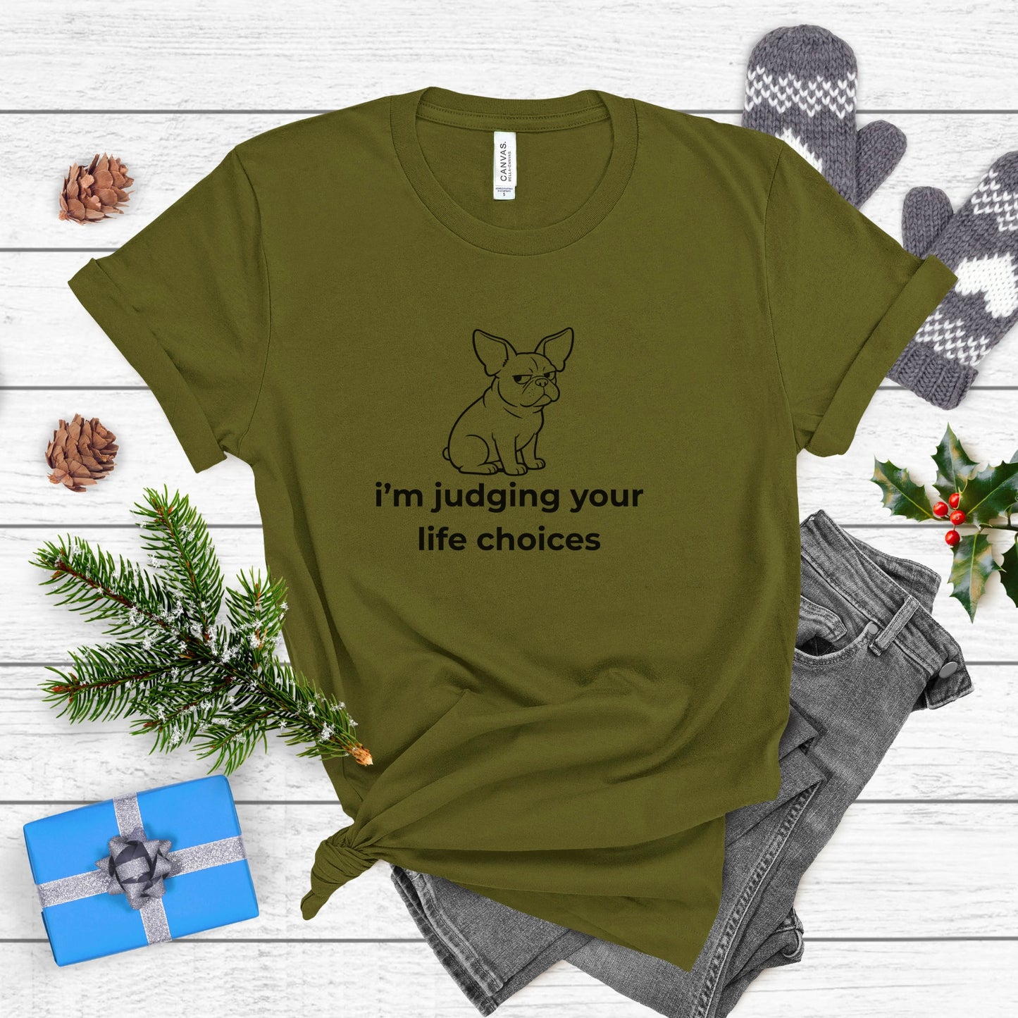 Green t-shirt with a dog graphic and text on a wooden surface with festive items.