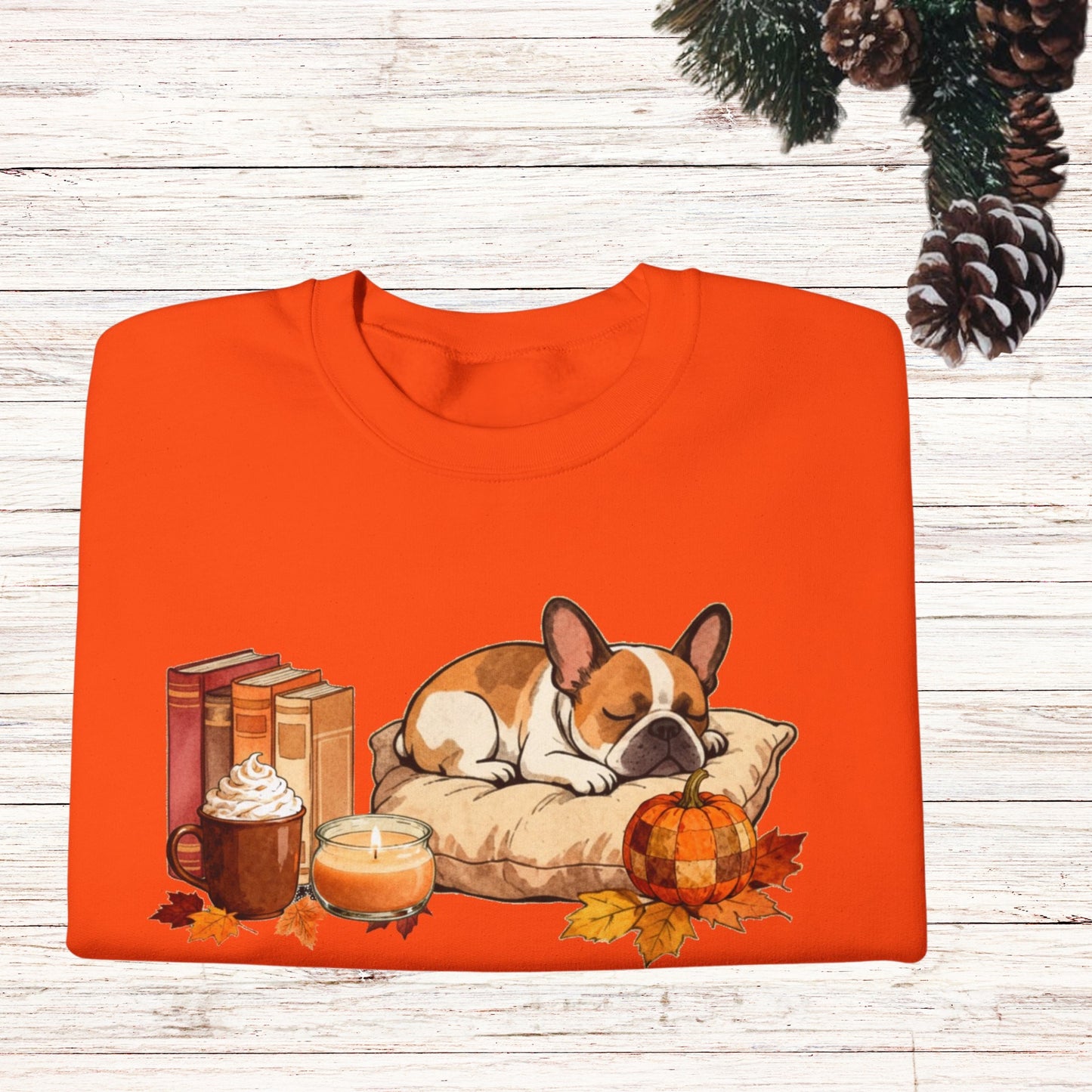 Orange sweatshirt with a dog, books, pumpkin, and candle design on a wooden surface.