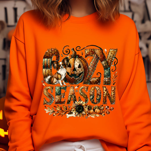 Orange sweatshirt with ' cozy season' design featuring pumpkins and a dog.