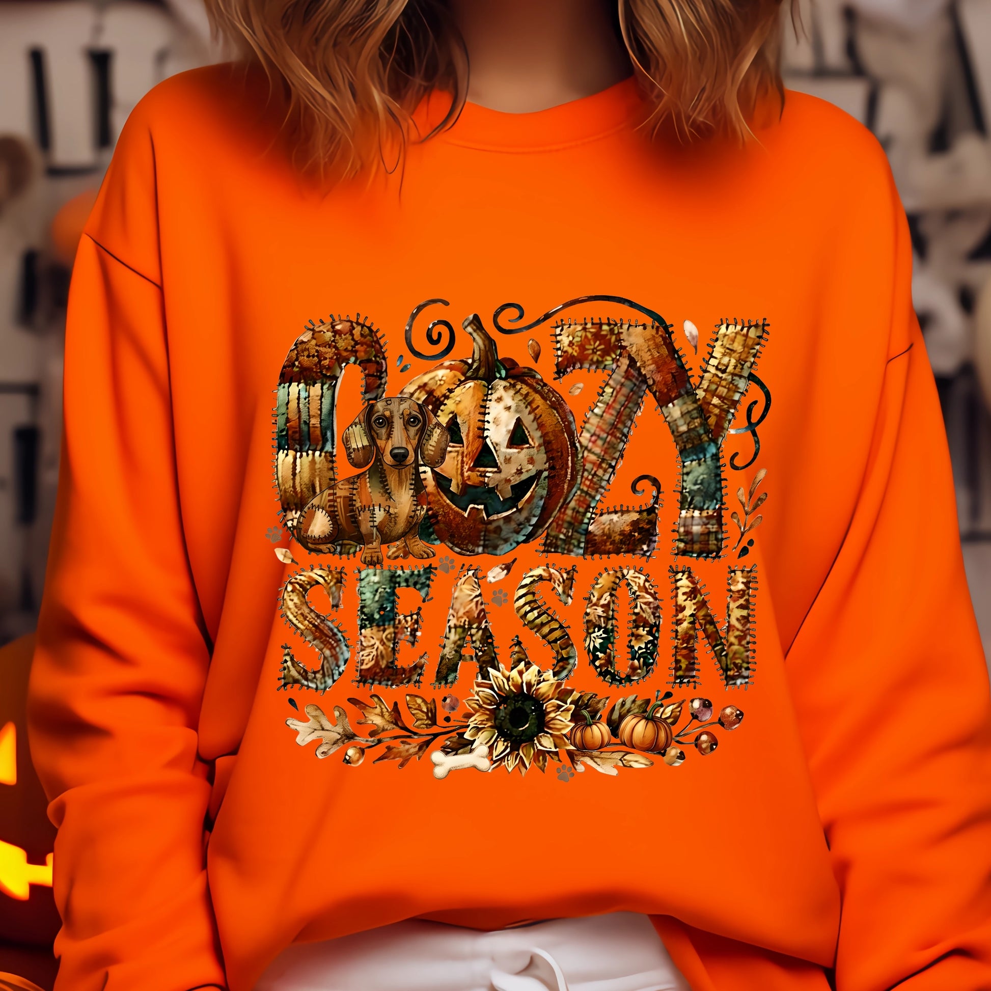 Cozy Season patchwork sweatshirt featuring a hidden Dachshound in autumn colors, surrounded by pumpkins, leaves, and a sunflower.Cozy patchwork sweatshirt with "Cozy Season" text, autumn colors, pumpkins, sunflower, and a hidden Dachshound motif.