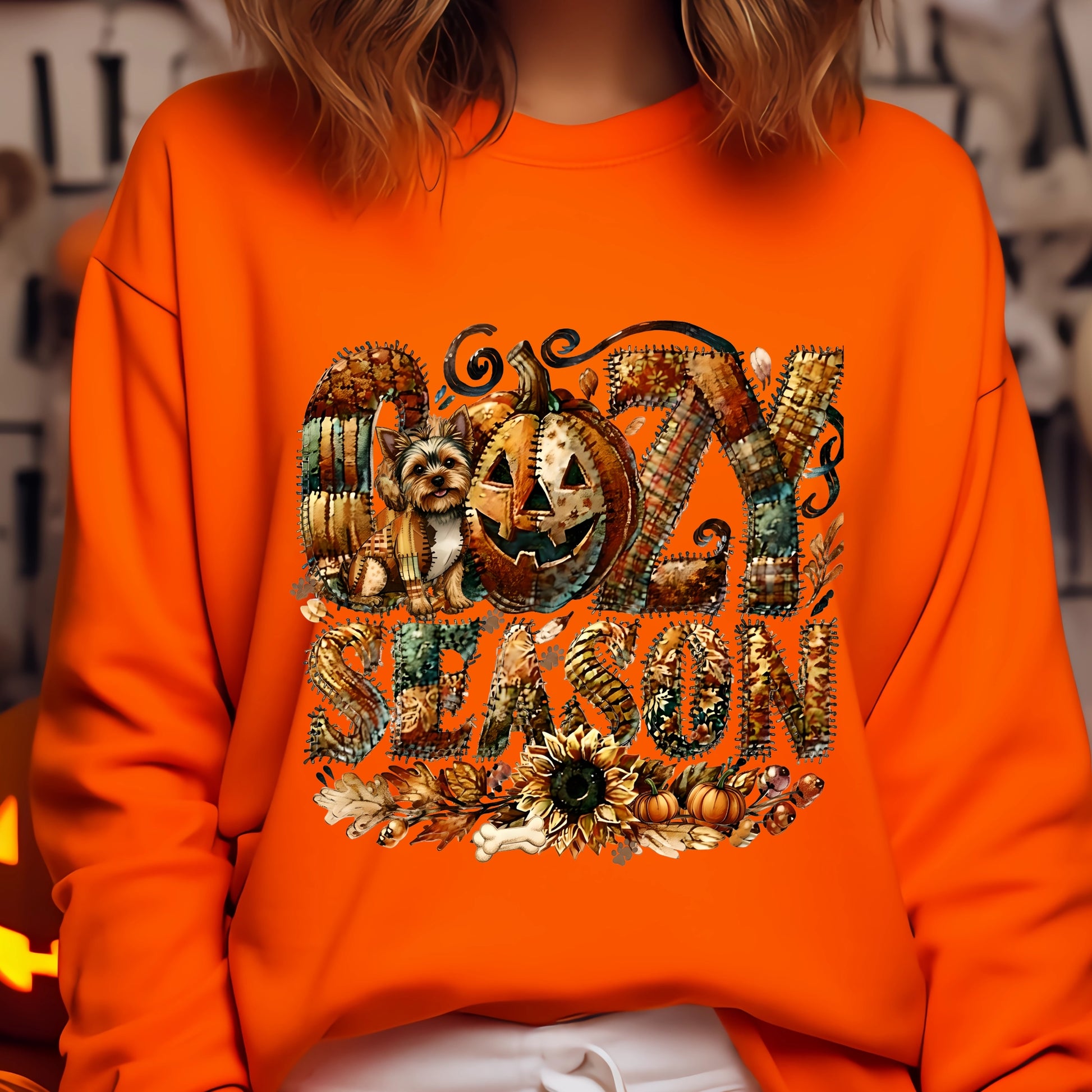 Person wearing an orange sweatshirt with 'Ozzy Season' design featuring pumpkins and a dog.